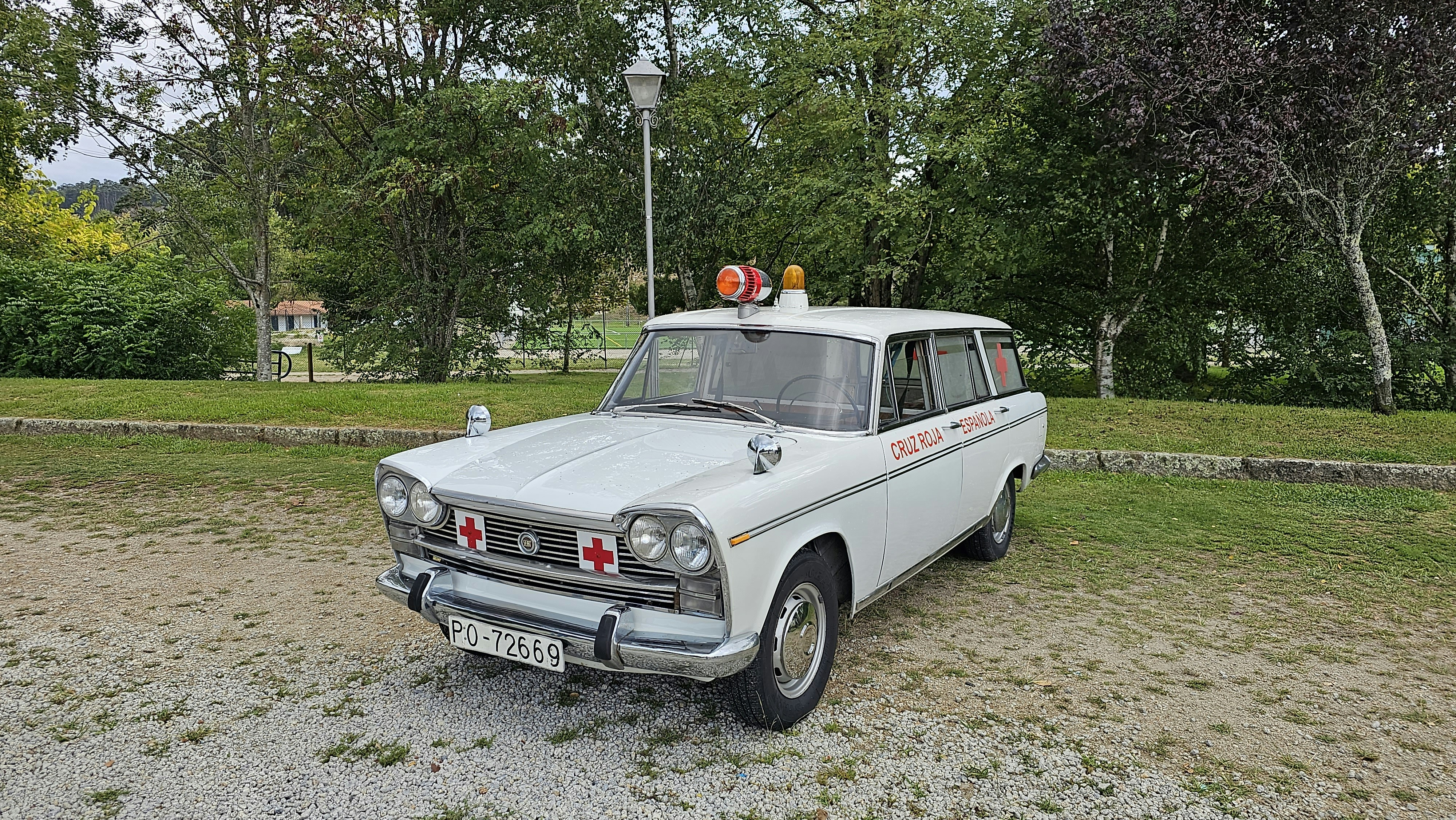 画像のキャプションはこちらです:砂利道に駐車された古い救急車。