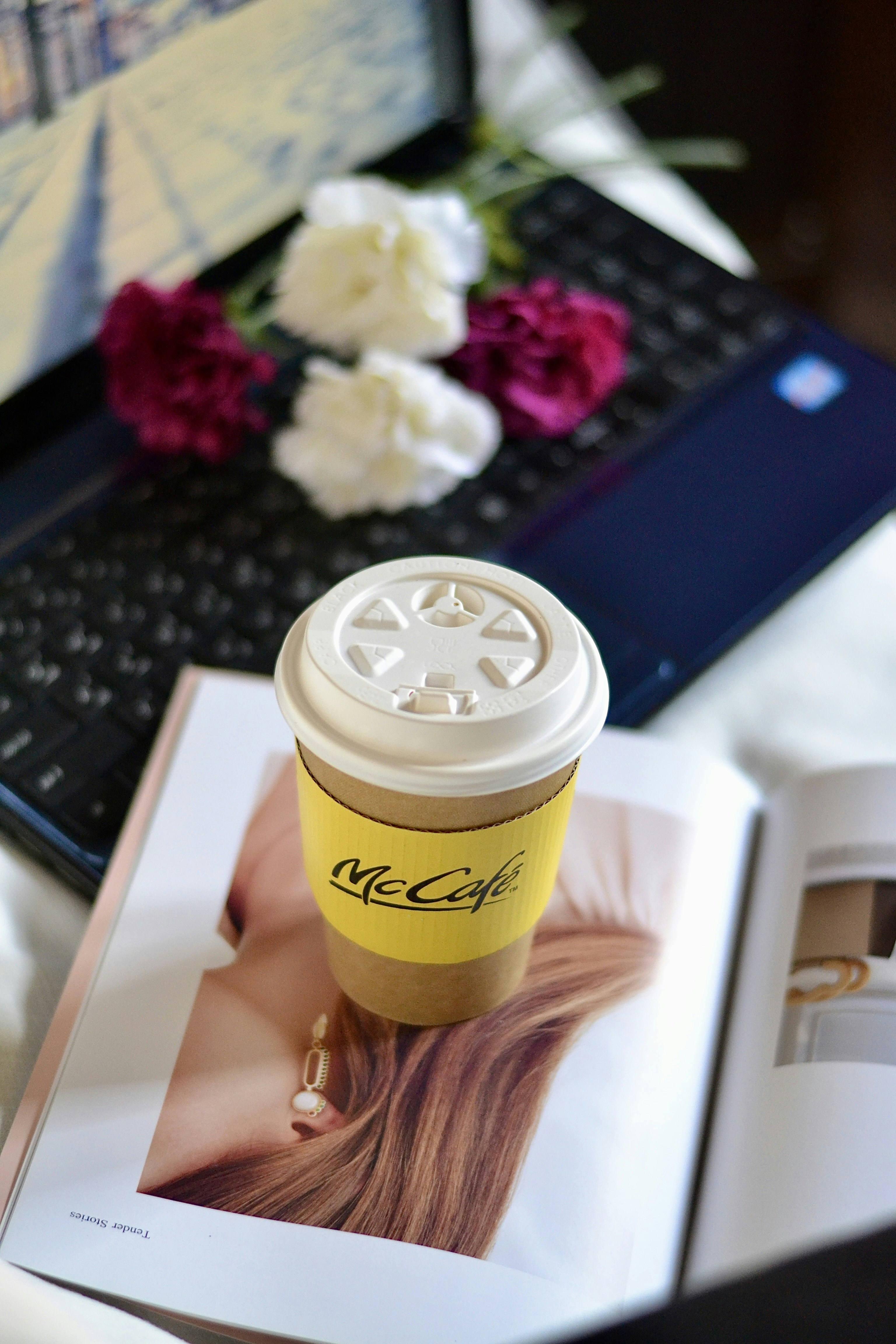 コーヒー、花、ノートパソコンが居心地の良いシーンを構成しています。
