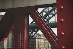 Red bridge structure with background buildings and bridge.