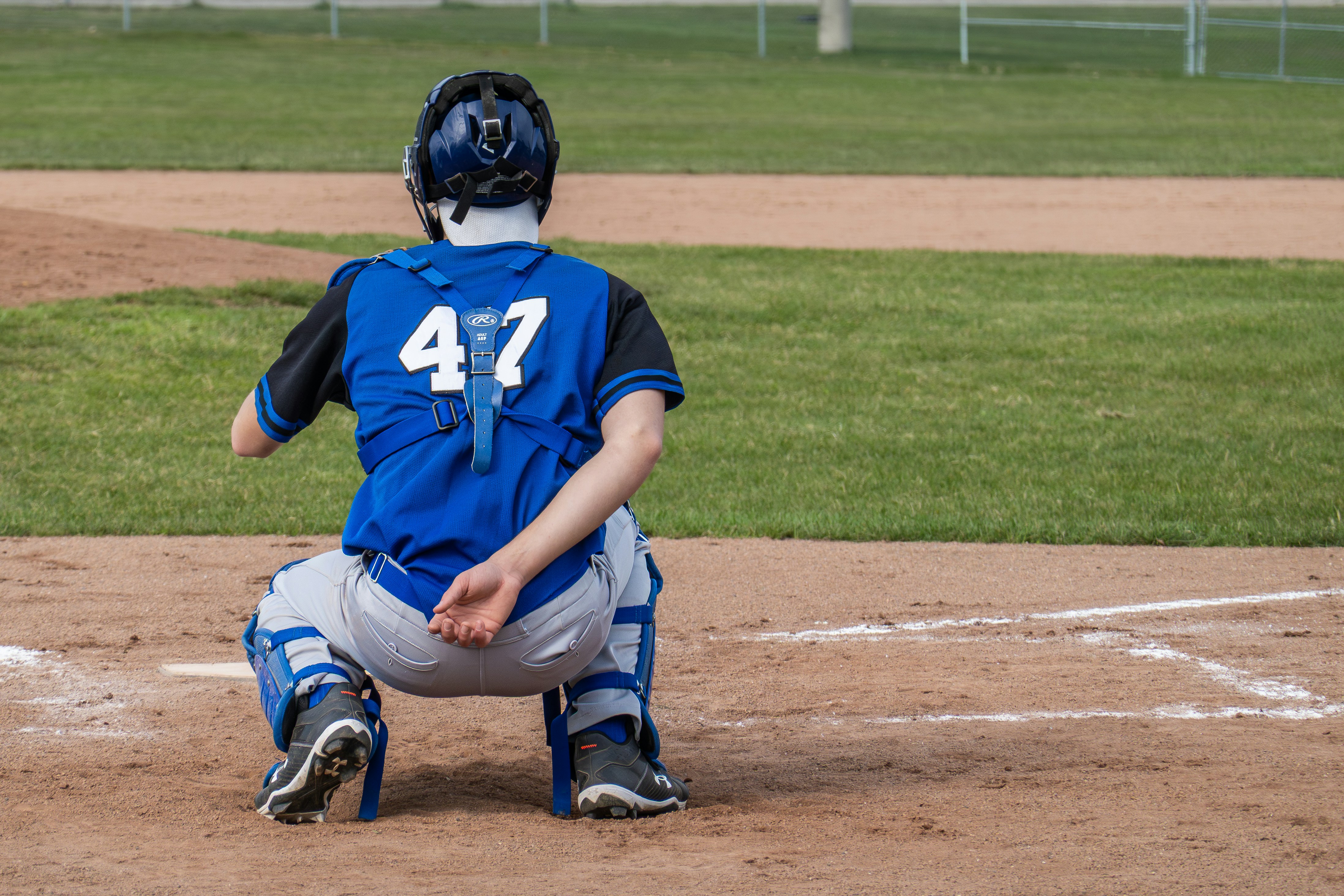 A baseball catcher crouches behind home plate.