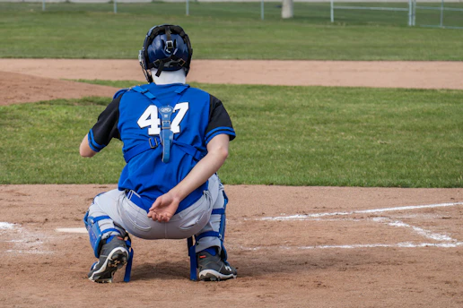 A baseball catcher crouches behind home plate.