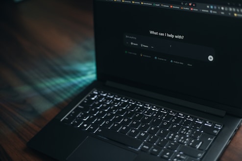 A laptop displays a search bar asking how it can help.