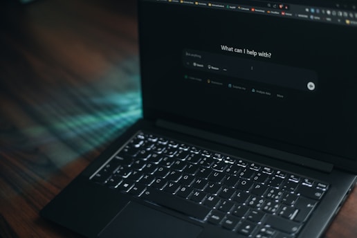 A laptop displays a search bar asking how it can help.