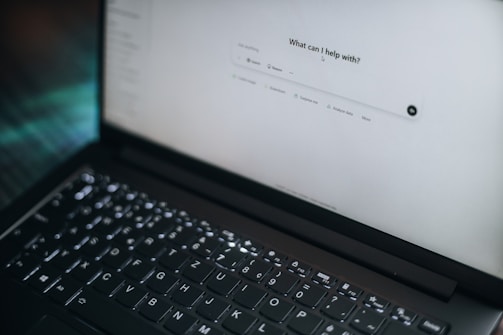 A laptop displays "what can i help with?"