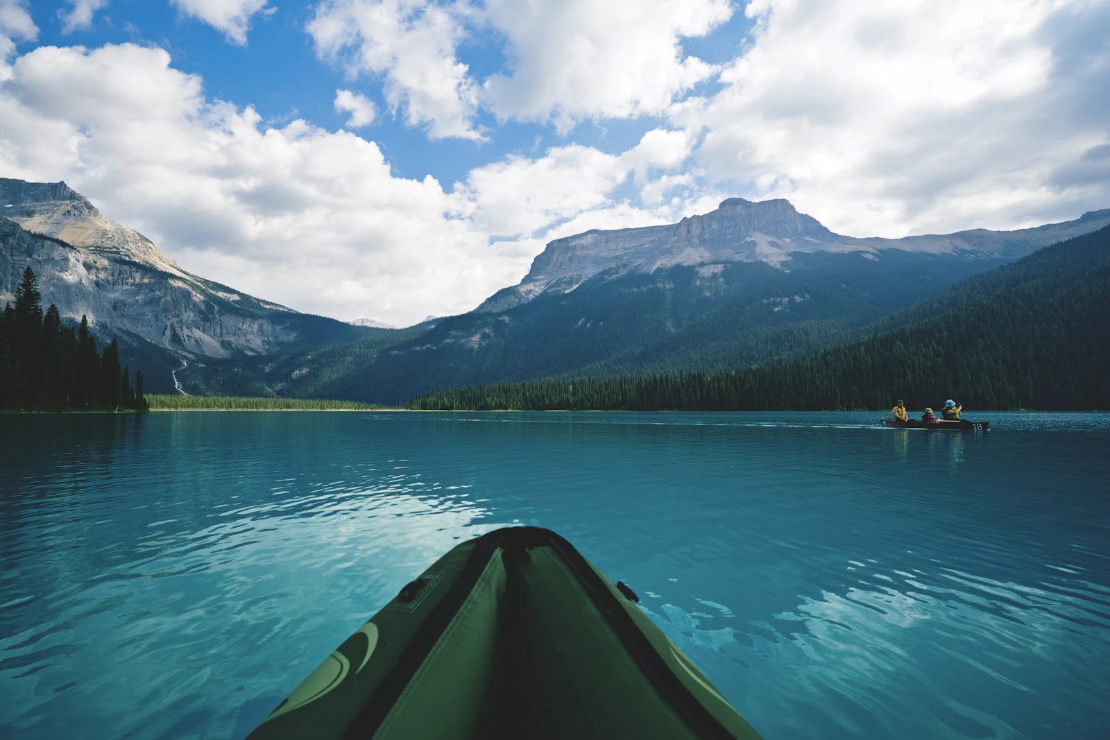 Kayakers crossing turquoise Emerald Lake beneath the Canadian mountains