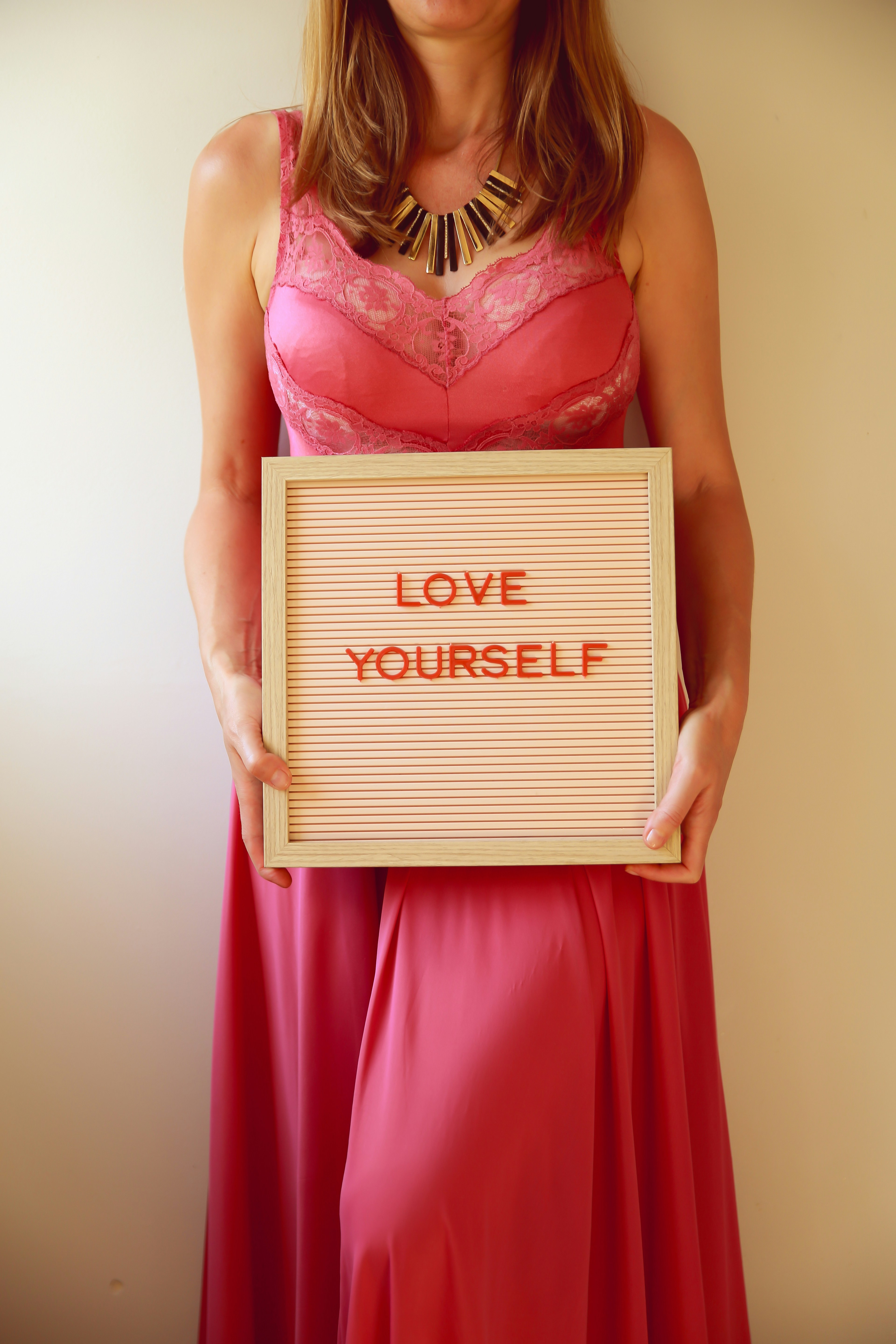 Die Frau hält ein Schild mit der Aufschrift "Liebe dich selbst".