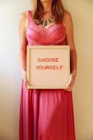 Woman in pink holds a sign saying "choose yourself."