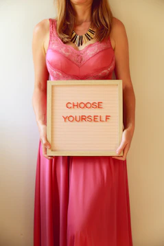 Woman in pink holds a sign saying "choose yourself."