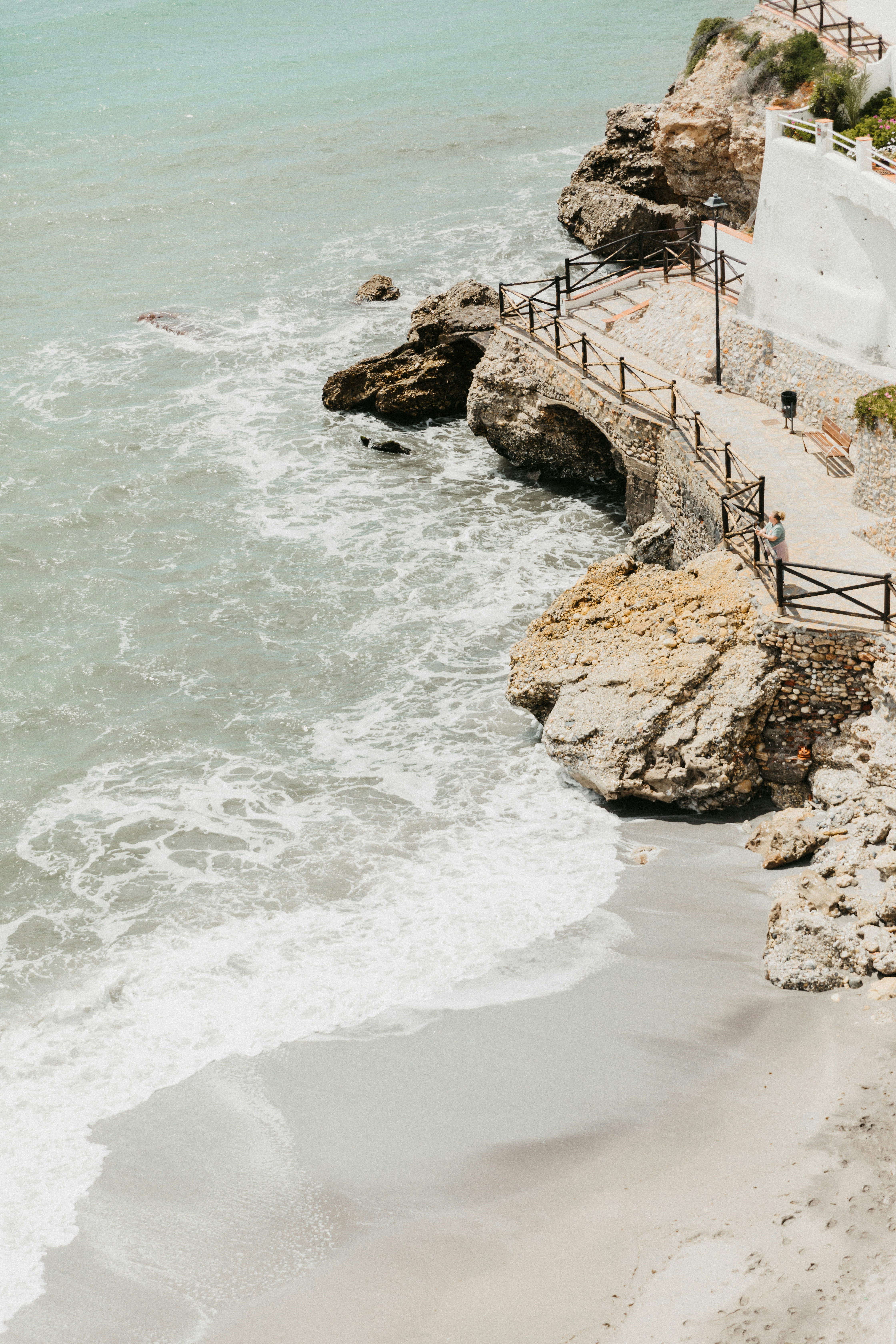 Rocky coastline with a beach and bridge.
