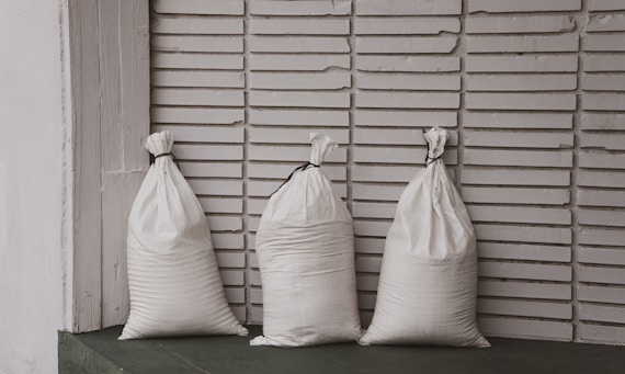Three white sacks stand against a striped wall.