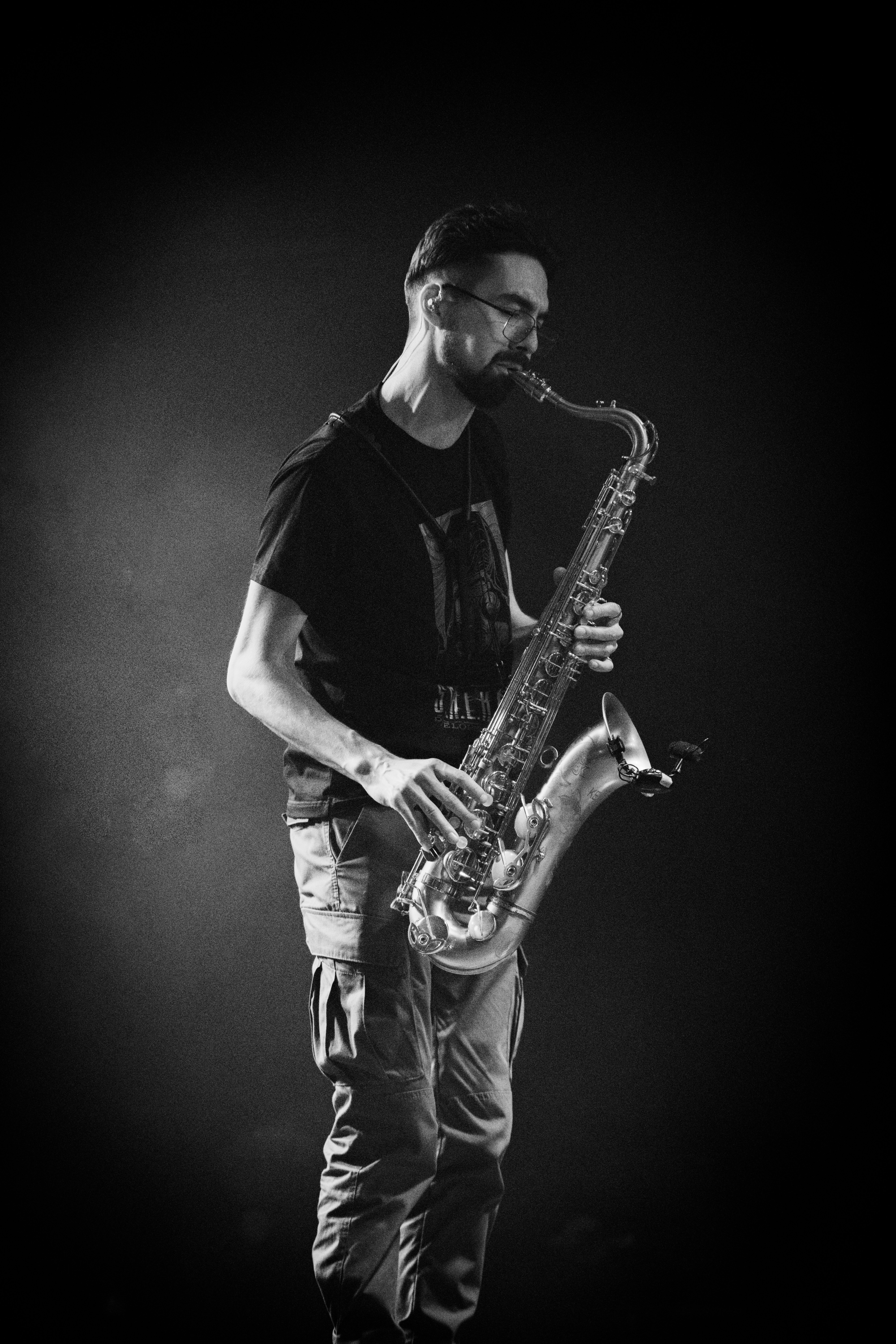 A man plays the saxophone in dramatic lighting.
