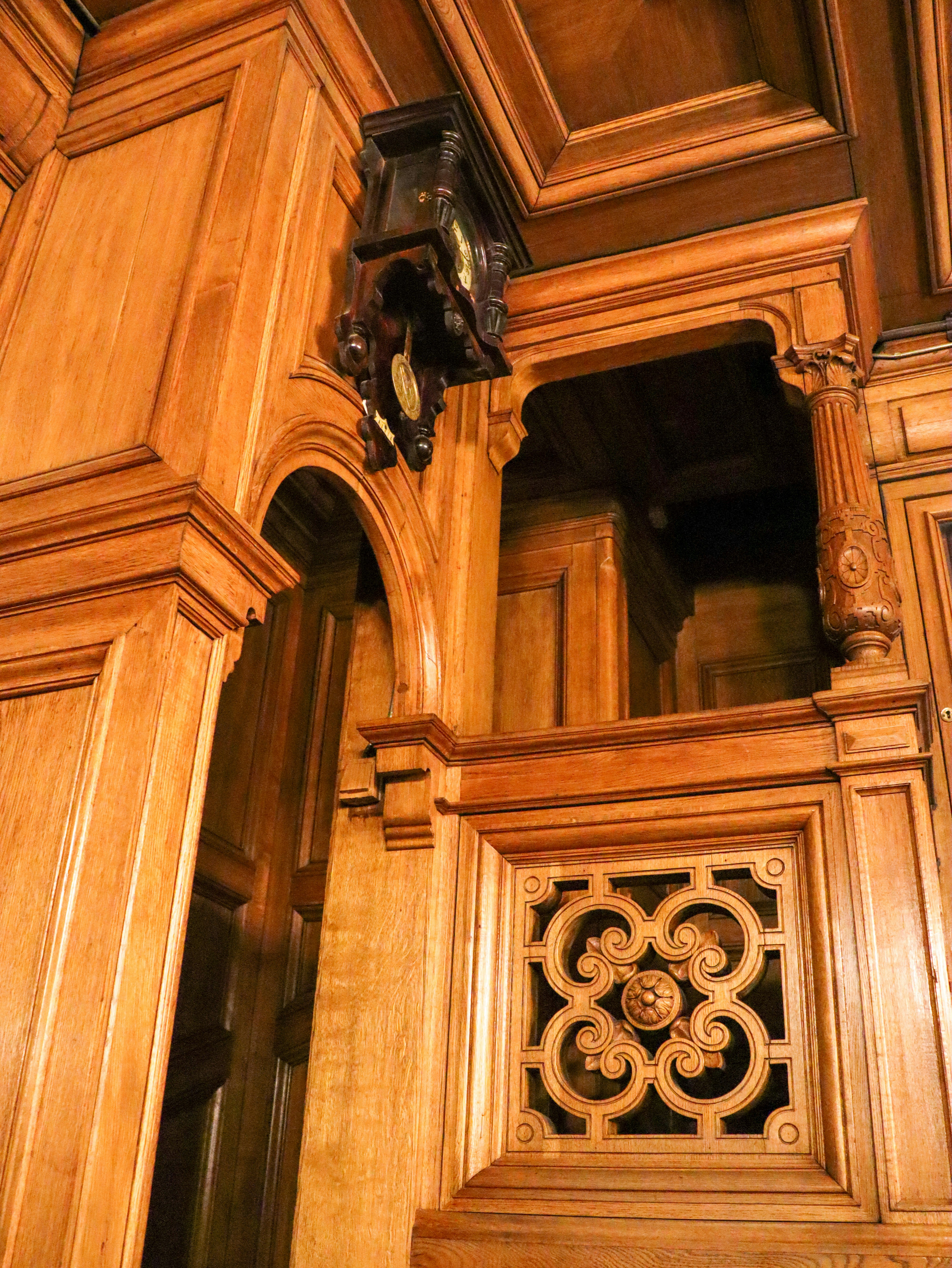 Intricate wooden paneling features a vintage clock.