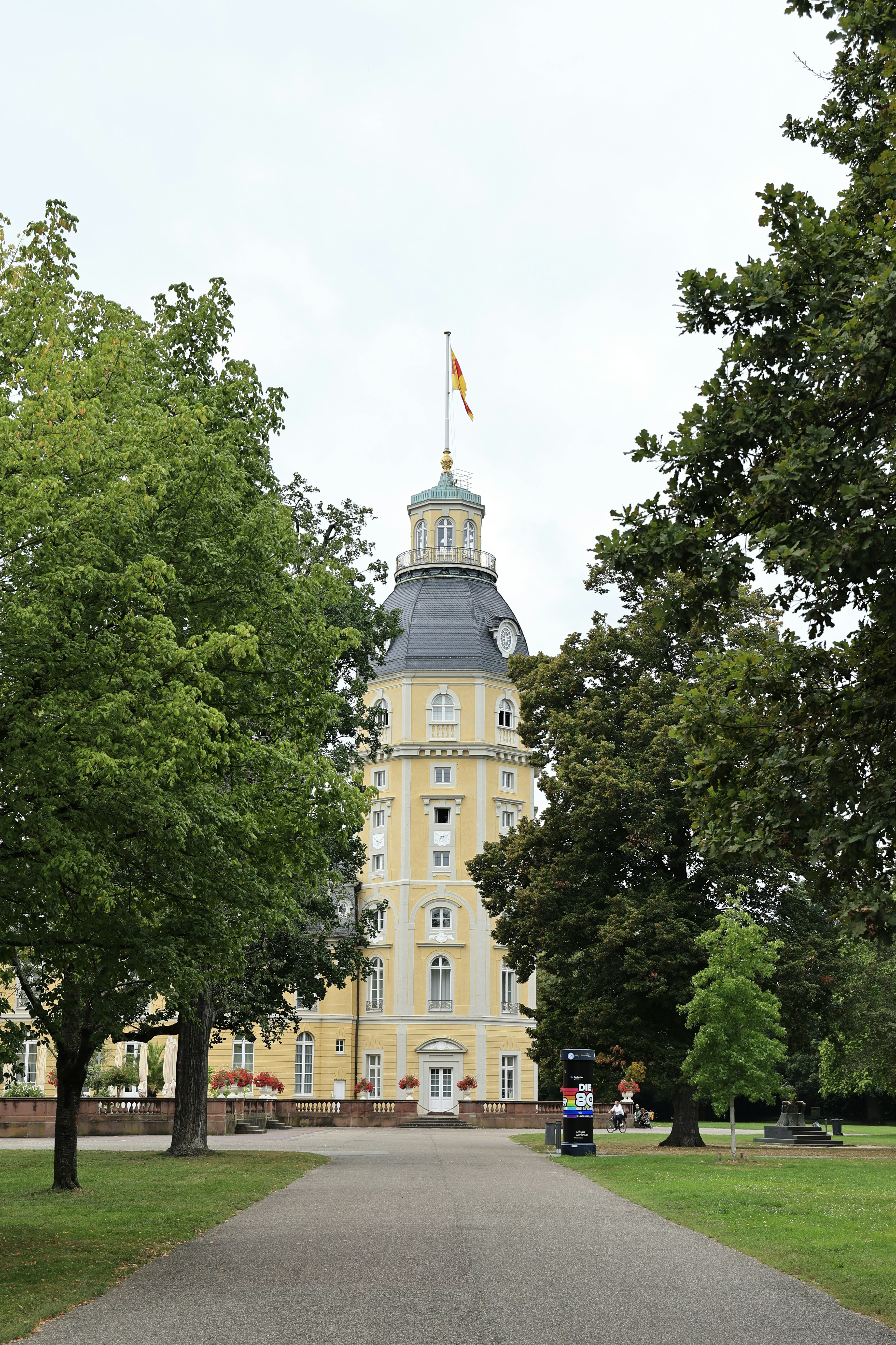 A yellow tower of a castle framed by trees.