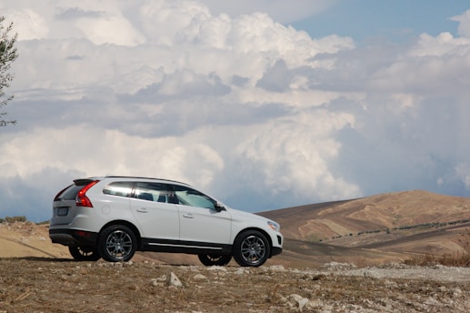 A white volvo suv is parked on a hill.