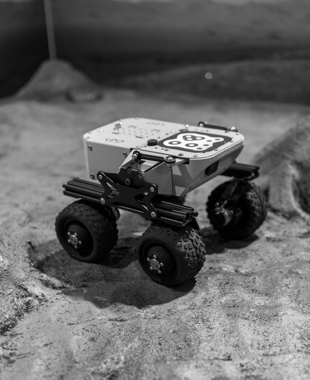 A robotic rover explores a desolate, lunar-like surface.