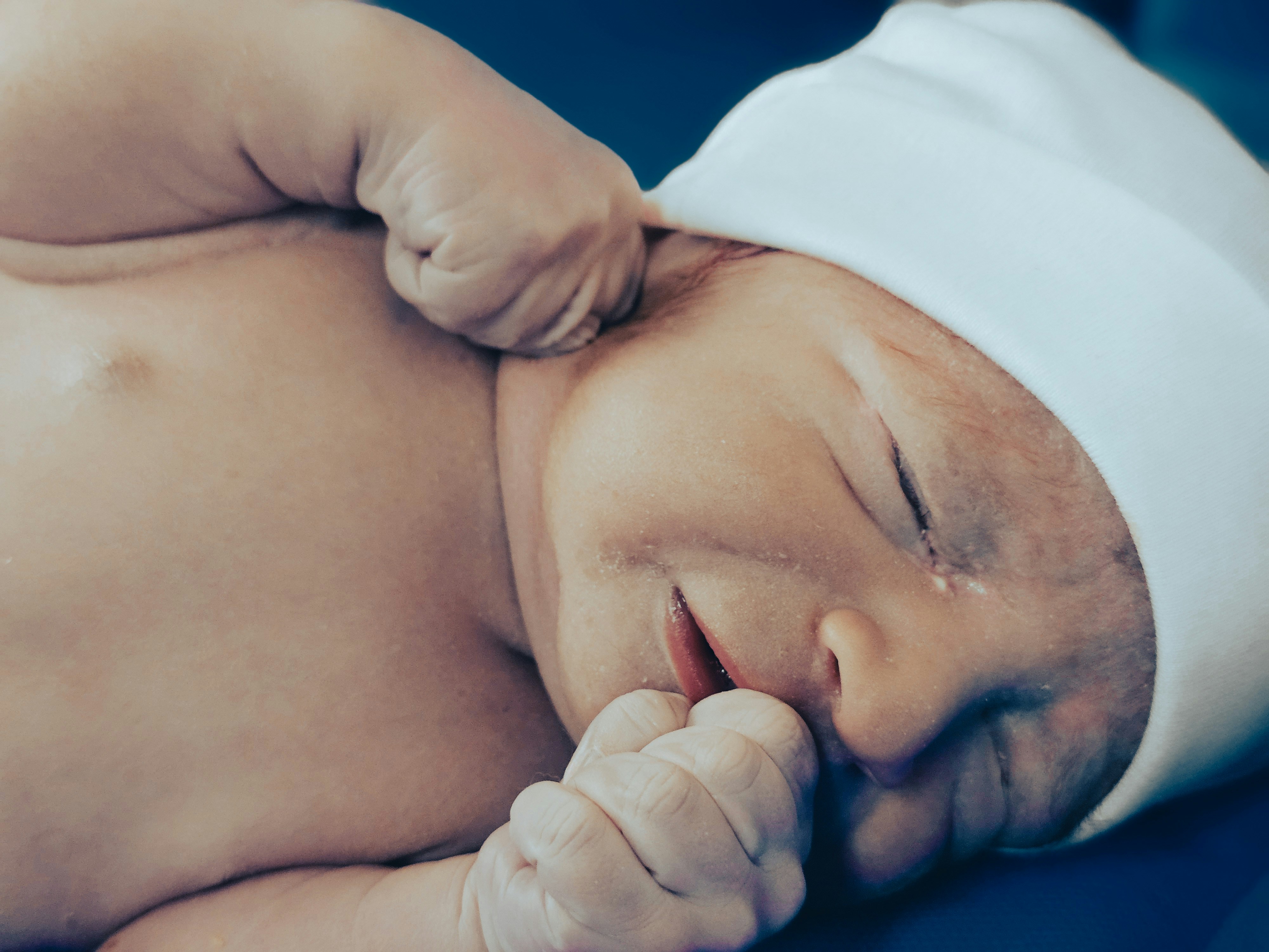 A newborn baby smiles happily, snuggled comfortably.