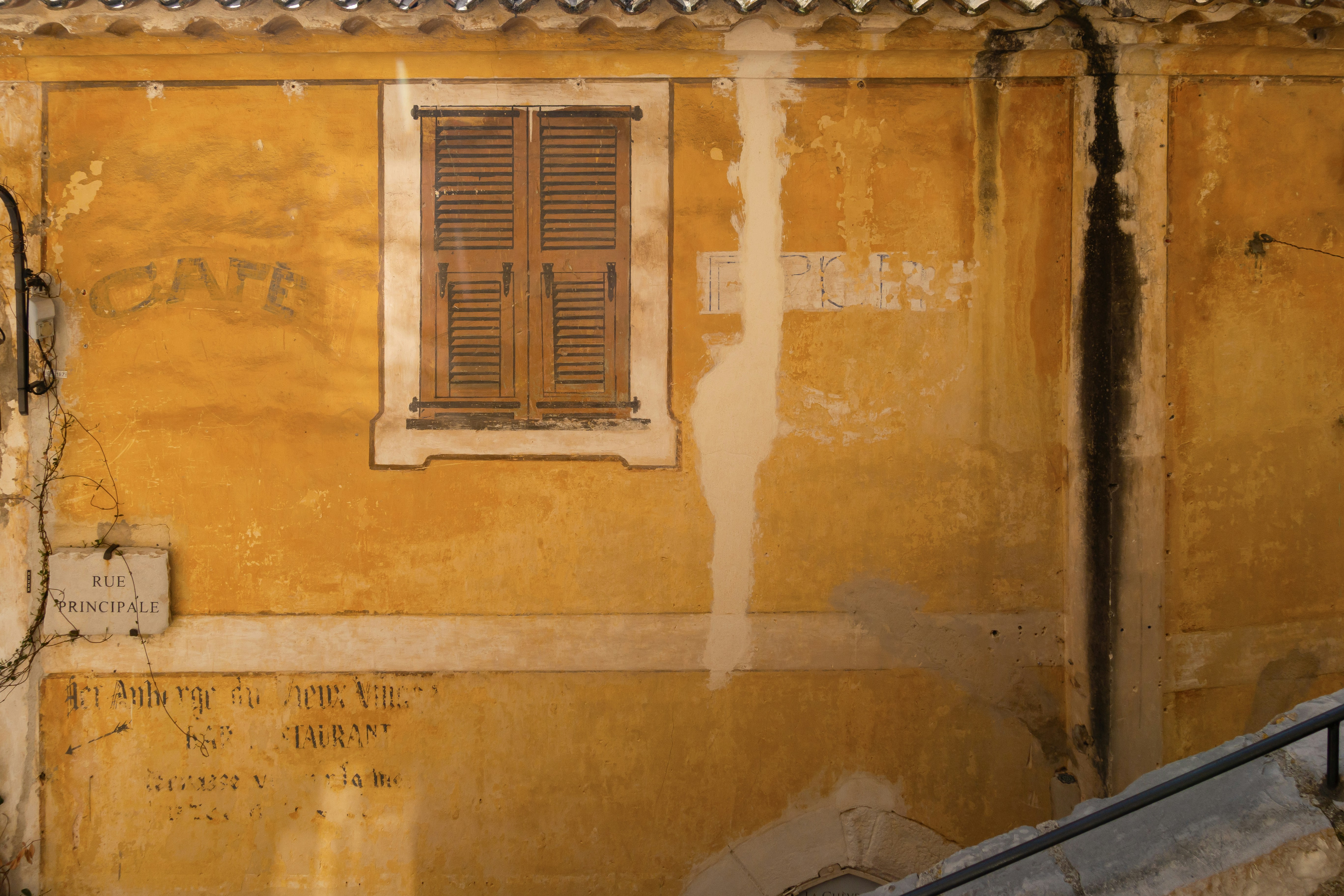 An old wall with a window and shutters.
