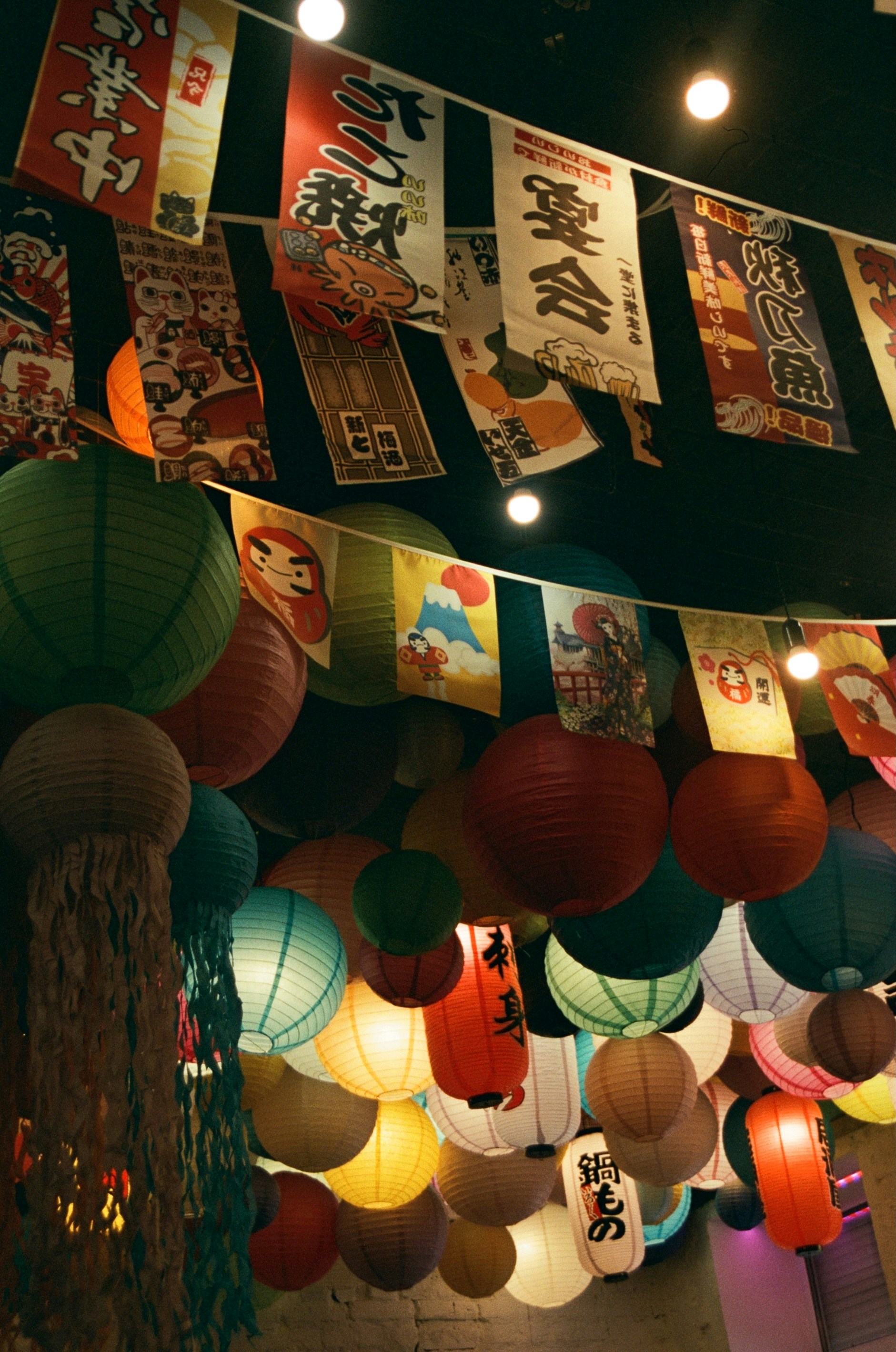 Japanese lanterns and banners decorate a ceiling.