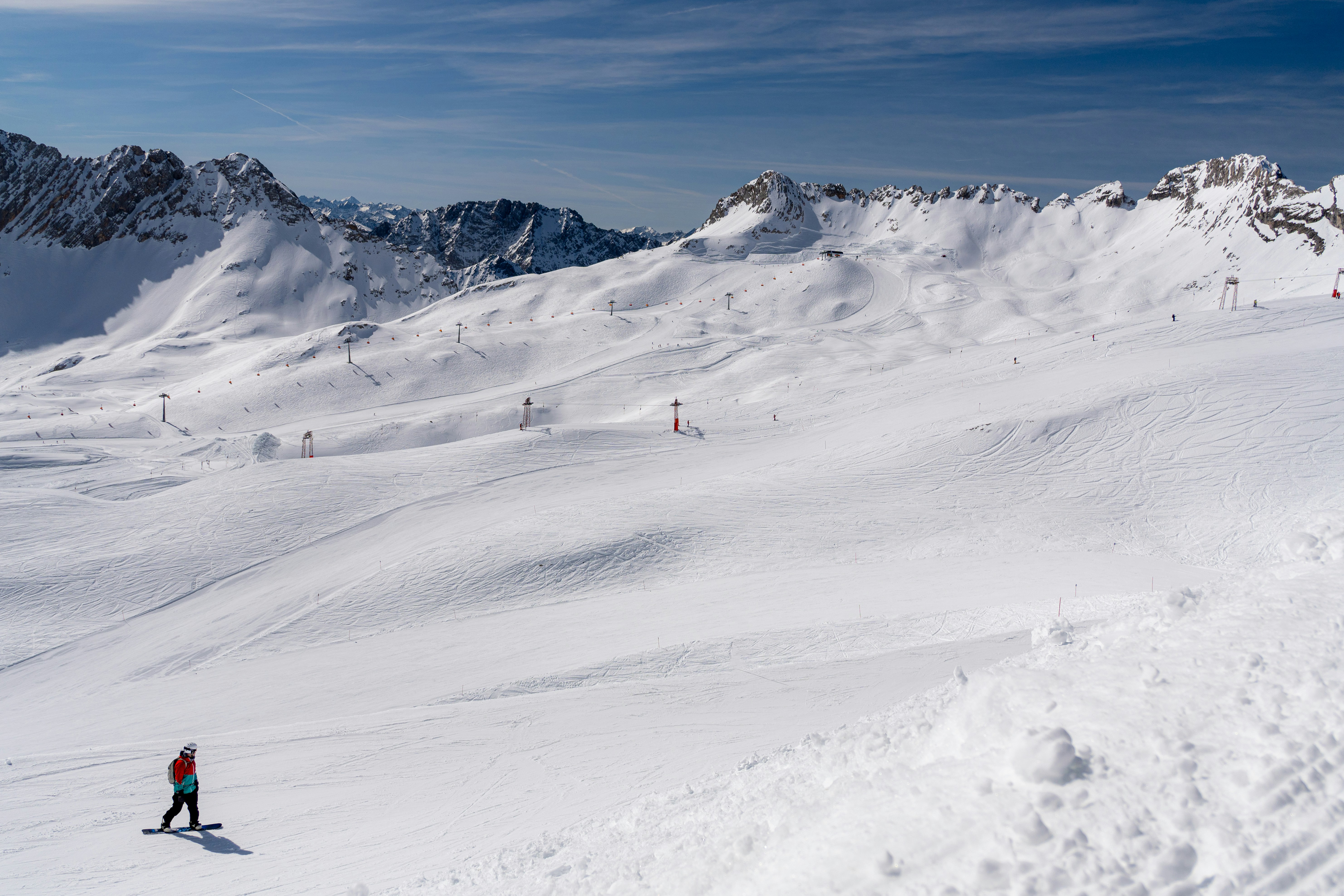 Snow-covered mountains and a skier under a blue sky., 