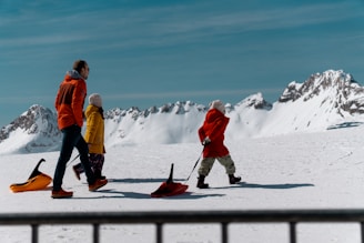 A family walks with sleds in a snowy landscape.