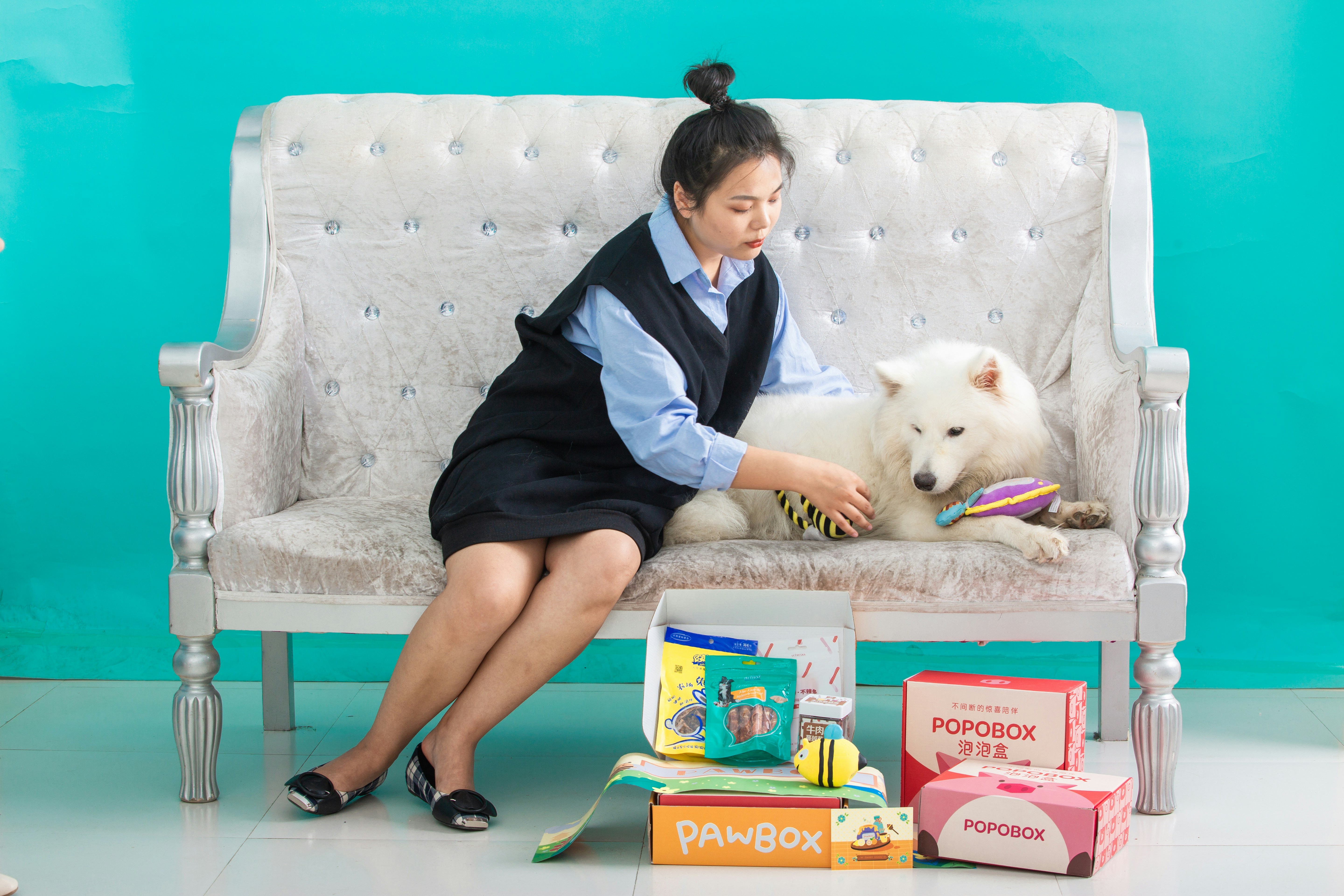 Woman pets her dog while sitting on a couch.
