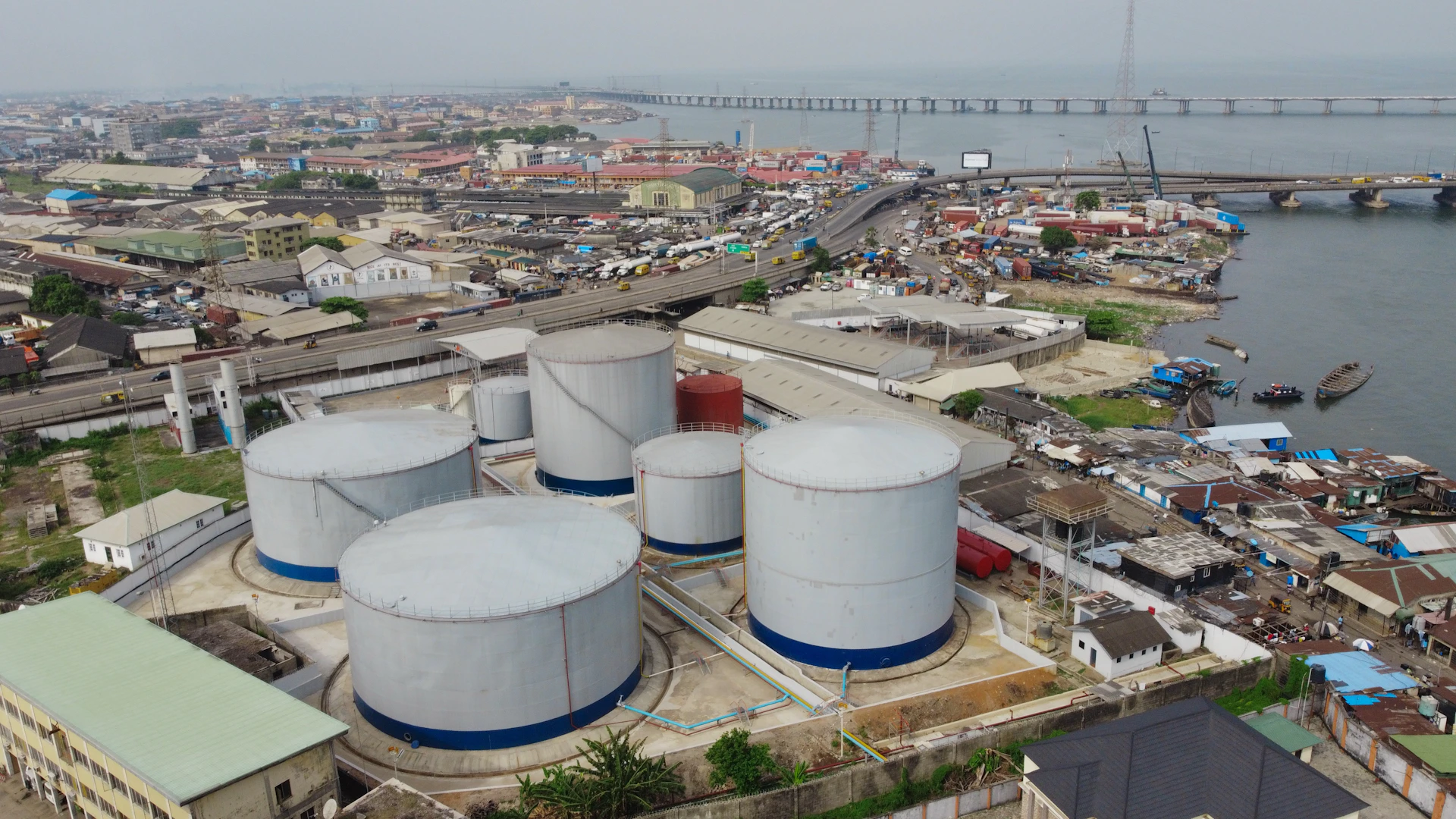 Large industrial tanks sit near a cityscape.