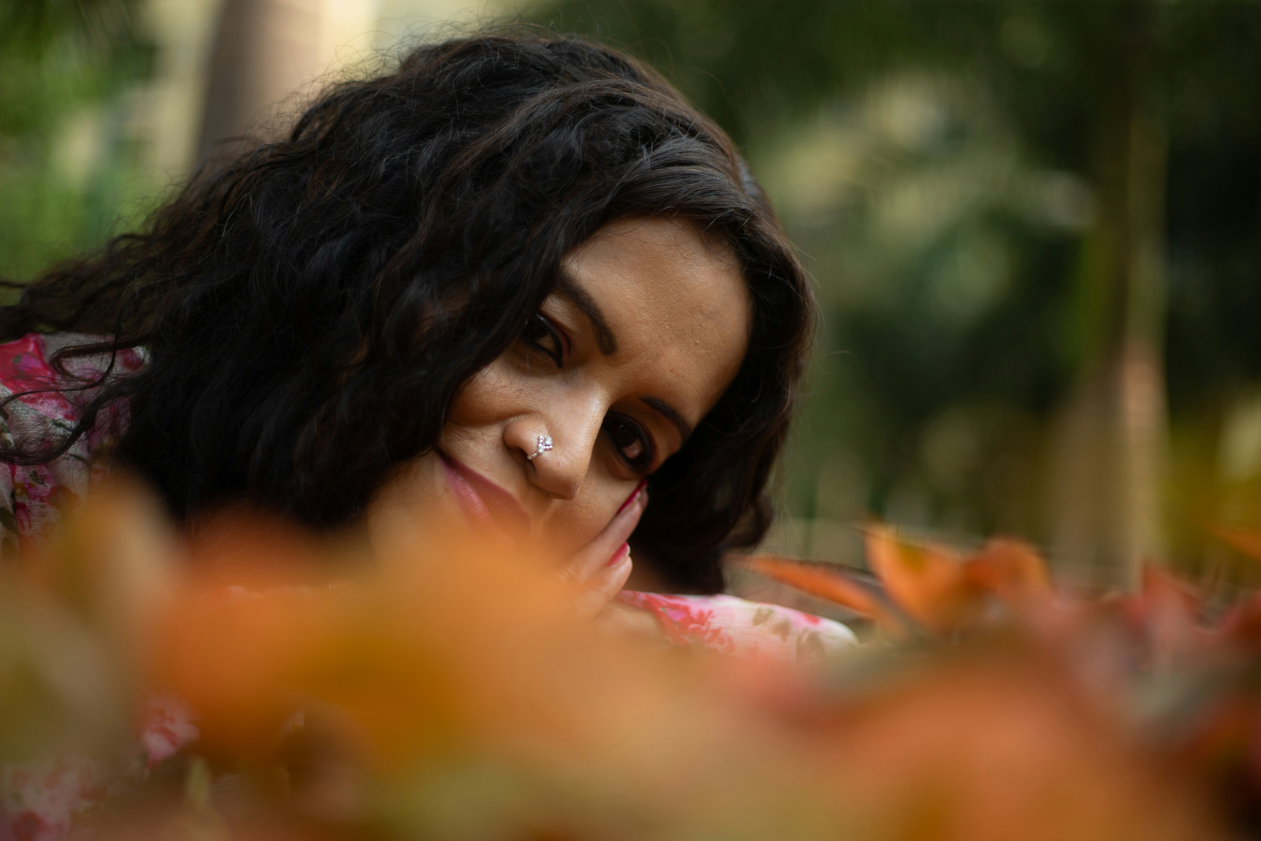 A woman poses among autumn leaves.
