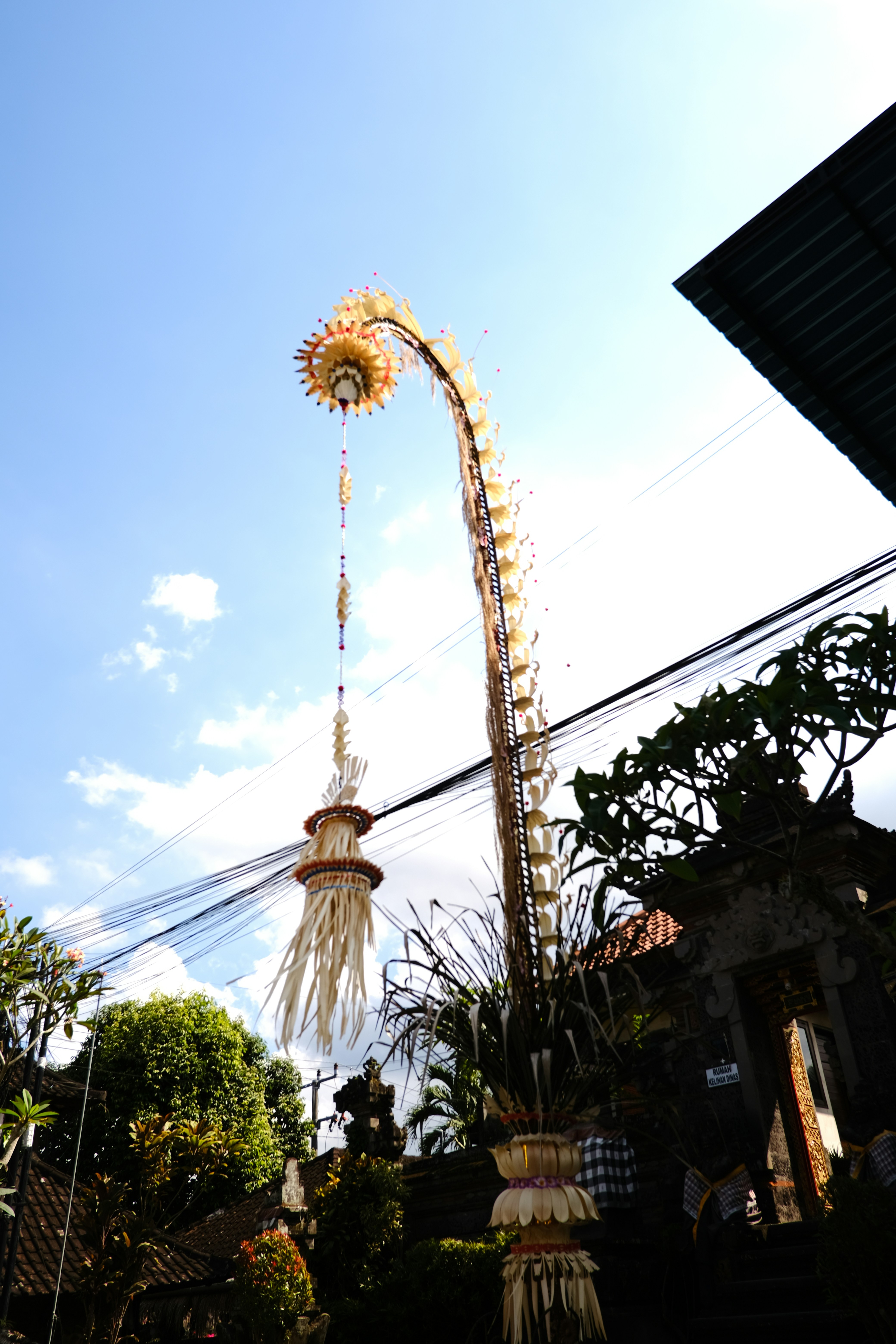 A tall balinese penjors decoration stands in the sky.