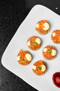 Caviar appetizers are arranged on a white plate.