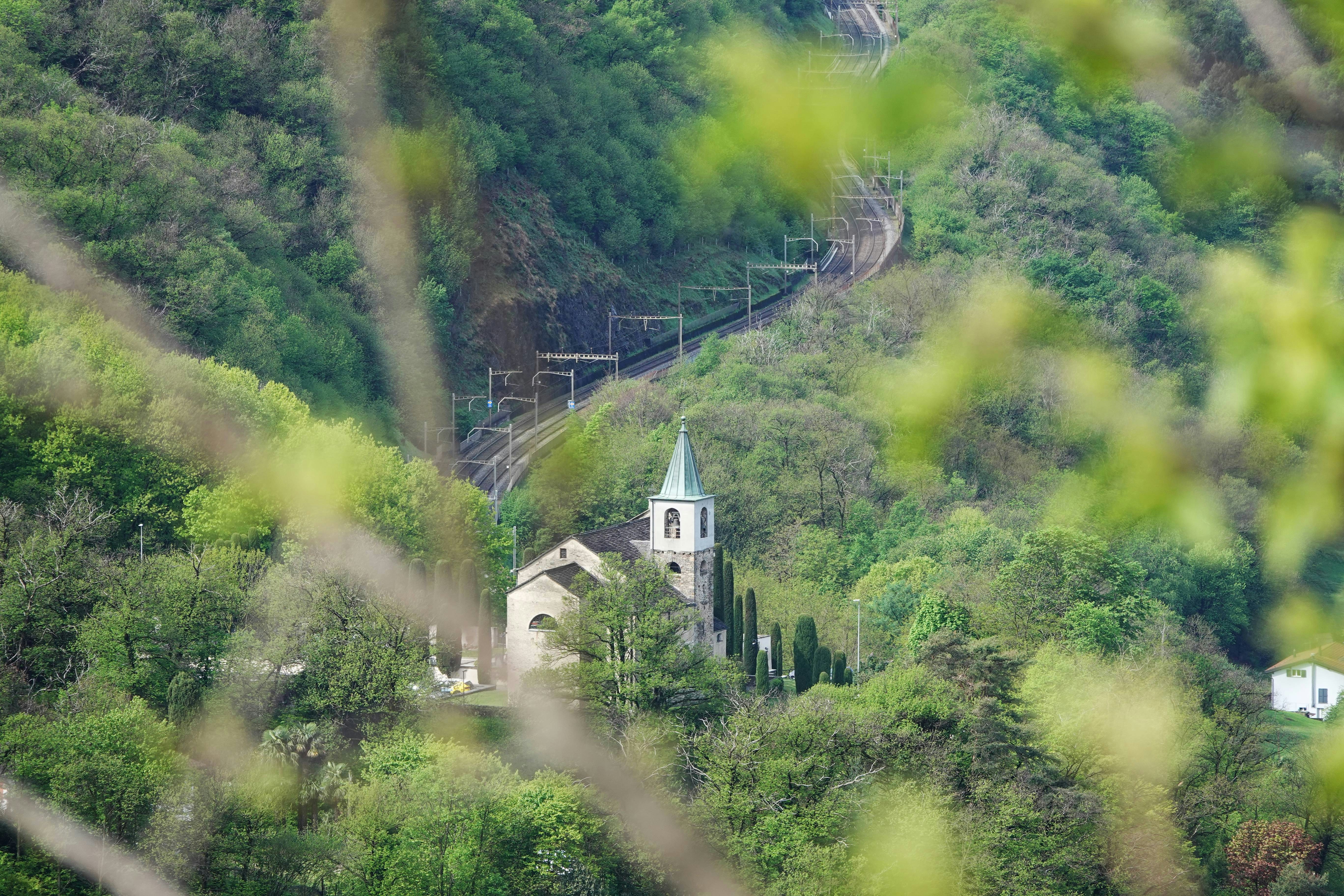 A church nestles among trees and a railway.