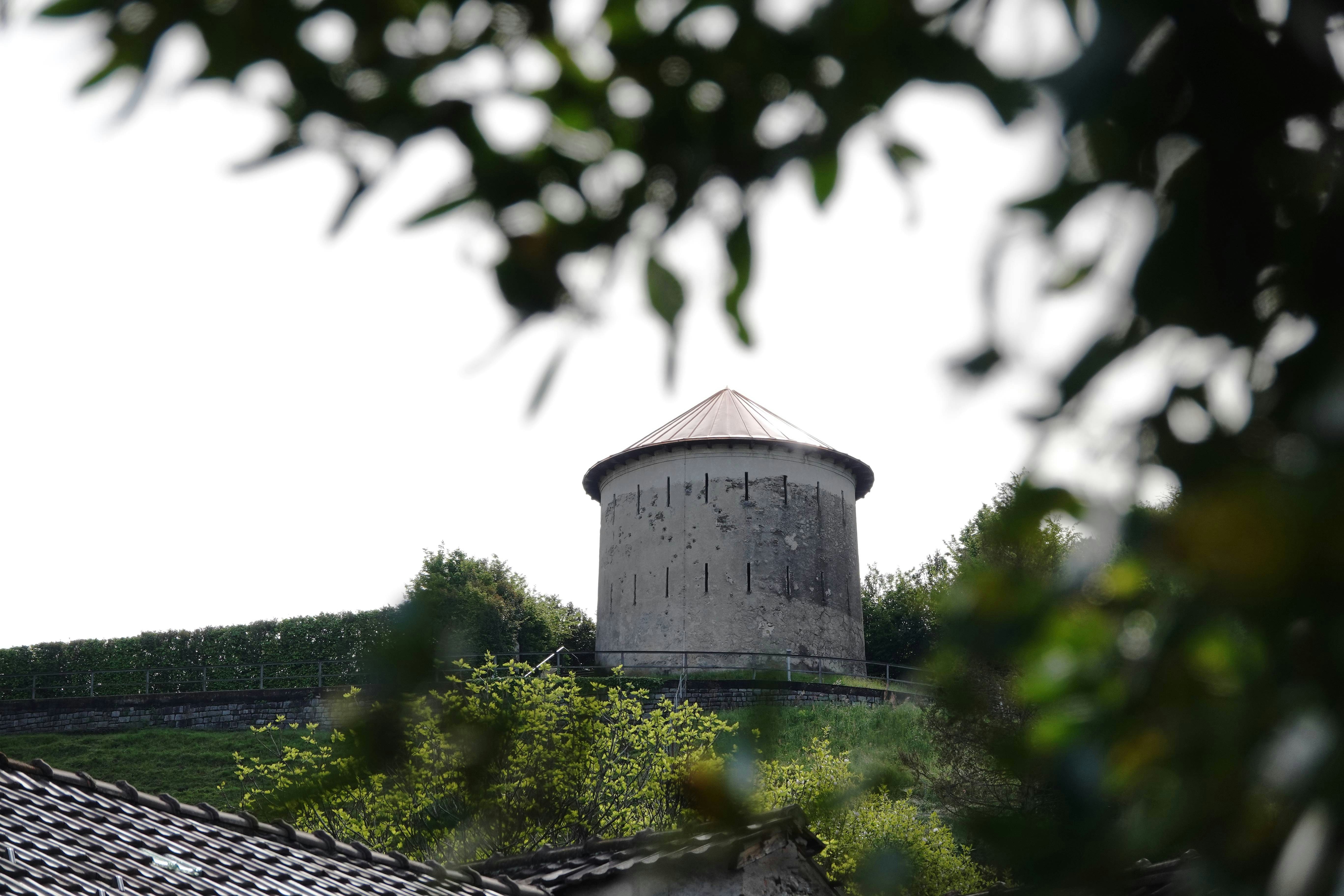 A round building sits atop a grassy hill.