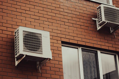 Air conditioners are attached to a brick building.