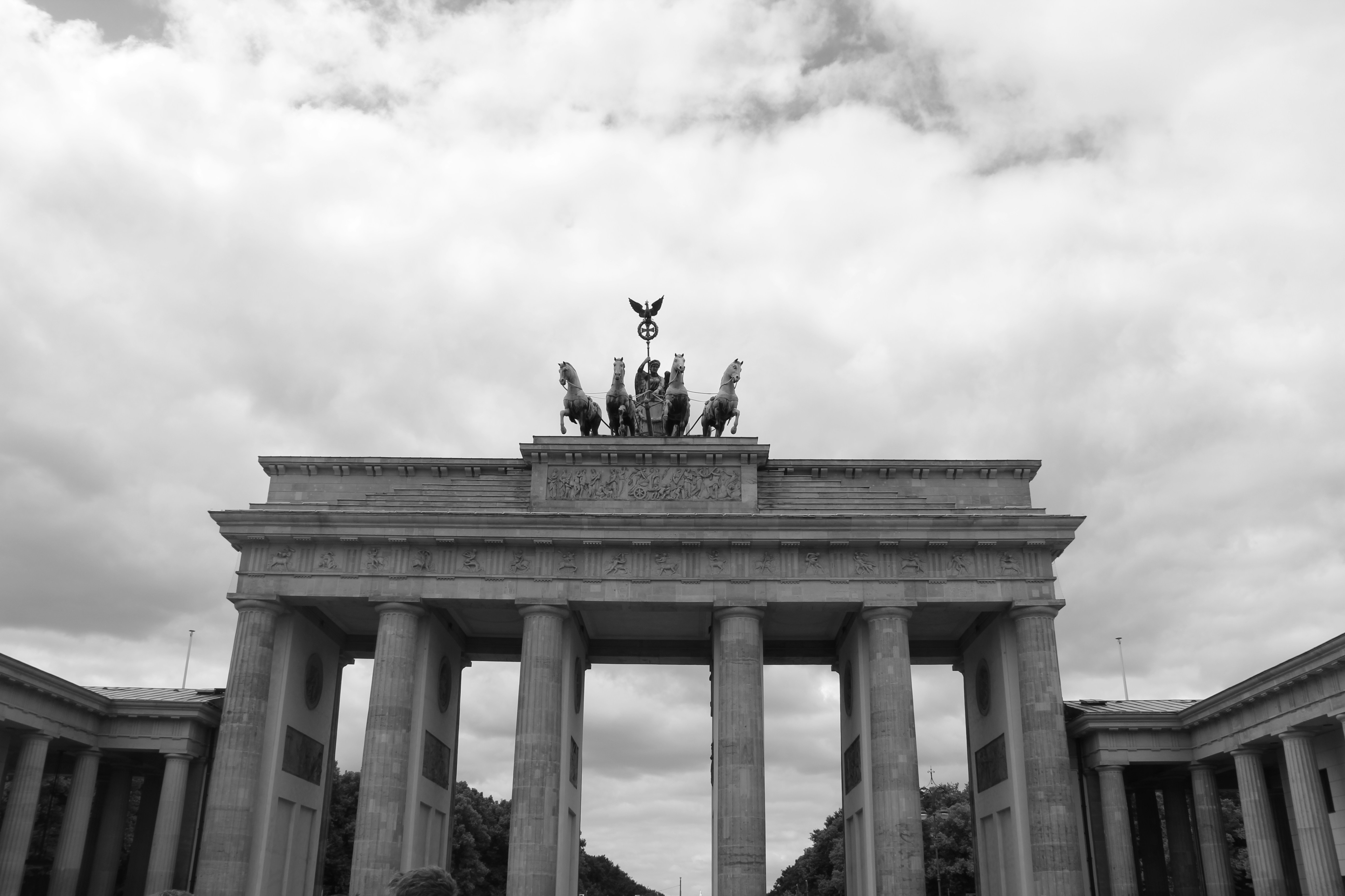 The brandenburg gate stands under cloudy skies.
