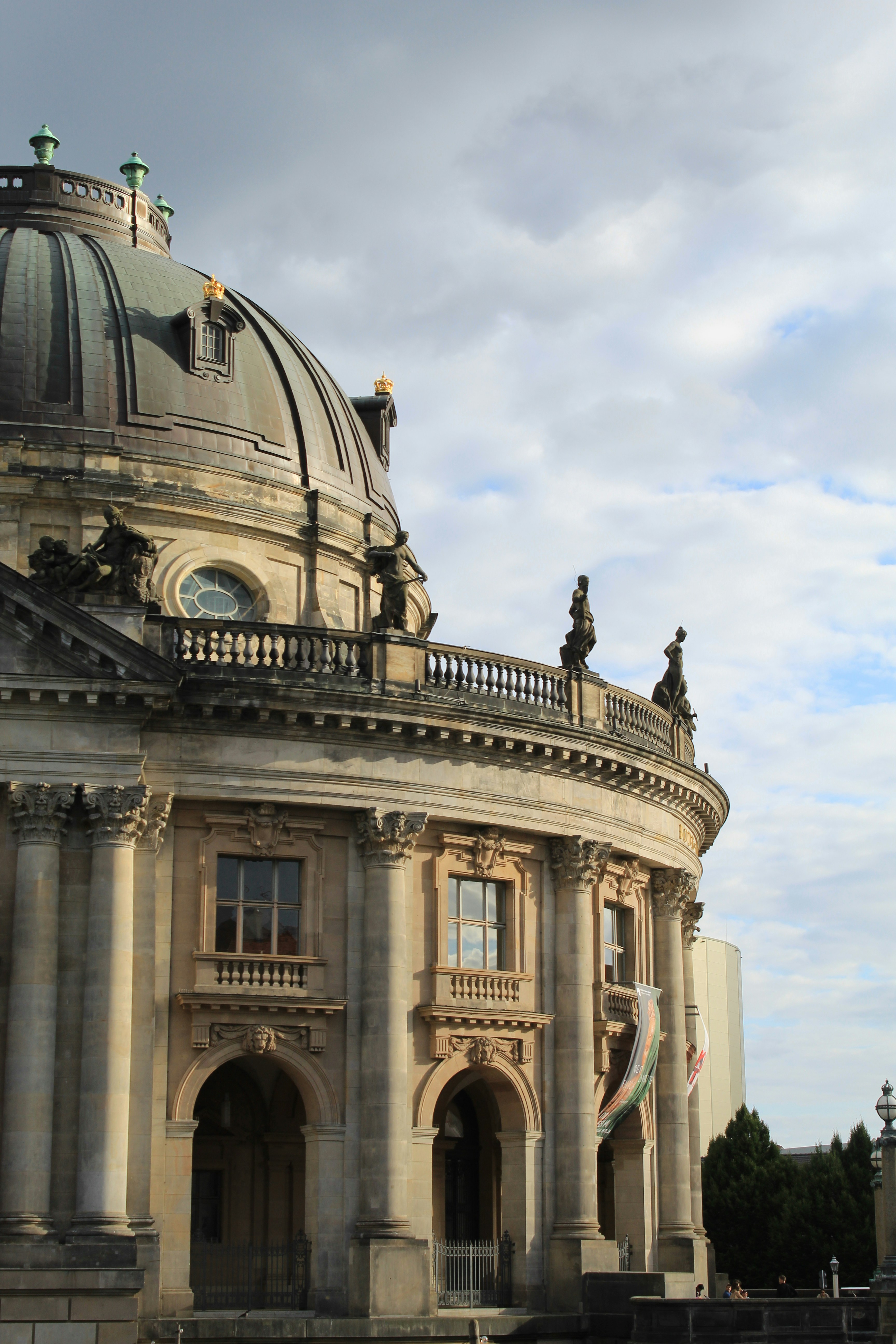 Photograph of a grand neoclassical domed building with a curved balcony lined by statues and arched entrances.