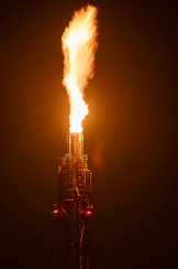 A tall flame flares upwards from a metal structure.