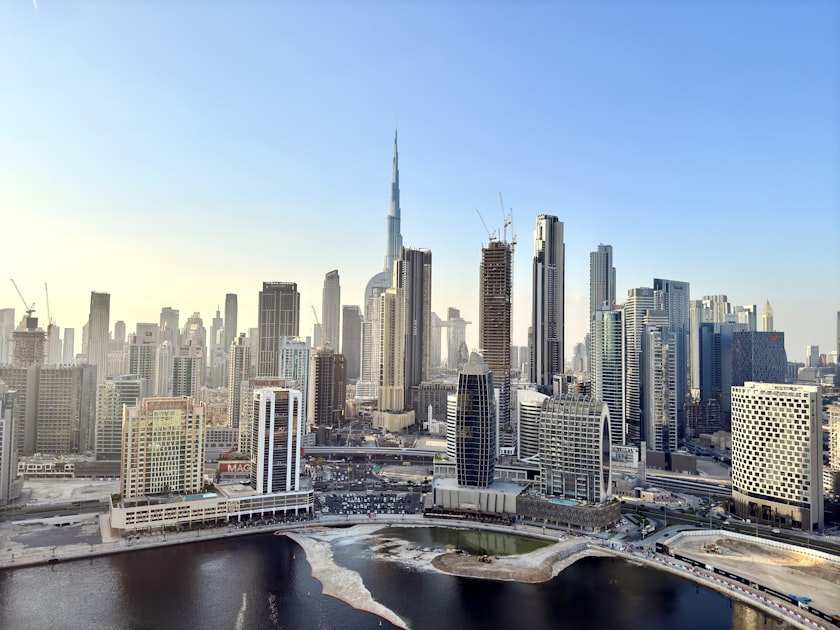 The downtown Dubai skyline is dominated by the Burj Khalifa rising above surrounding towers under a clear blue sky.