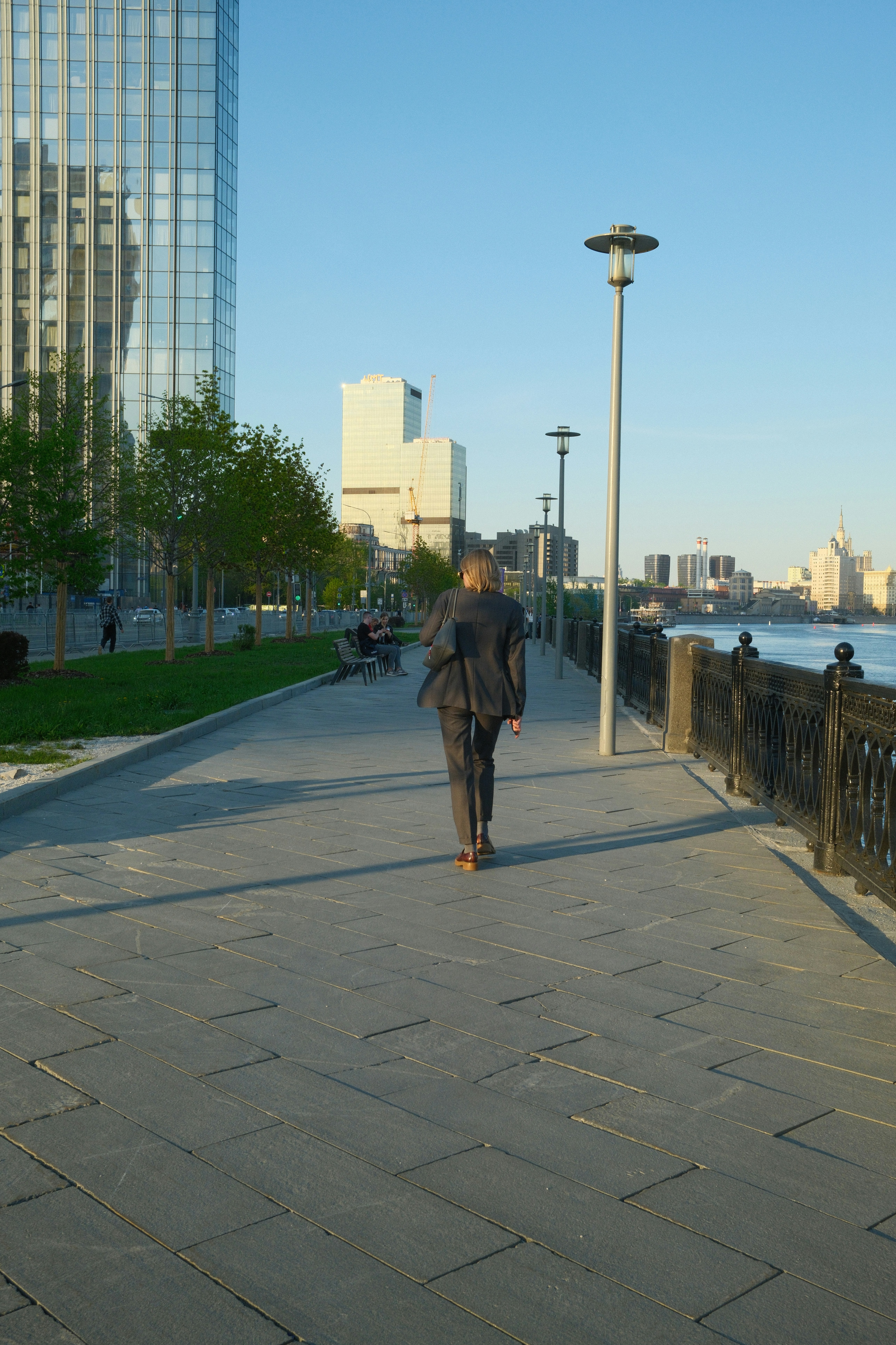 Eine Person geht einen Weg entlang einer Uferpromenade entlang.