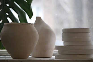 Ceramic pottery and plates sit on a windowsill.