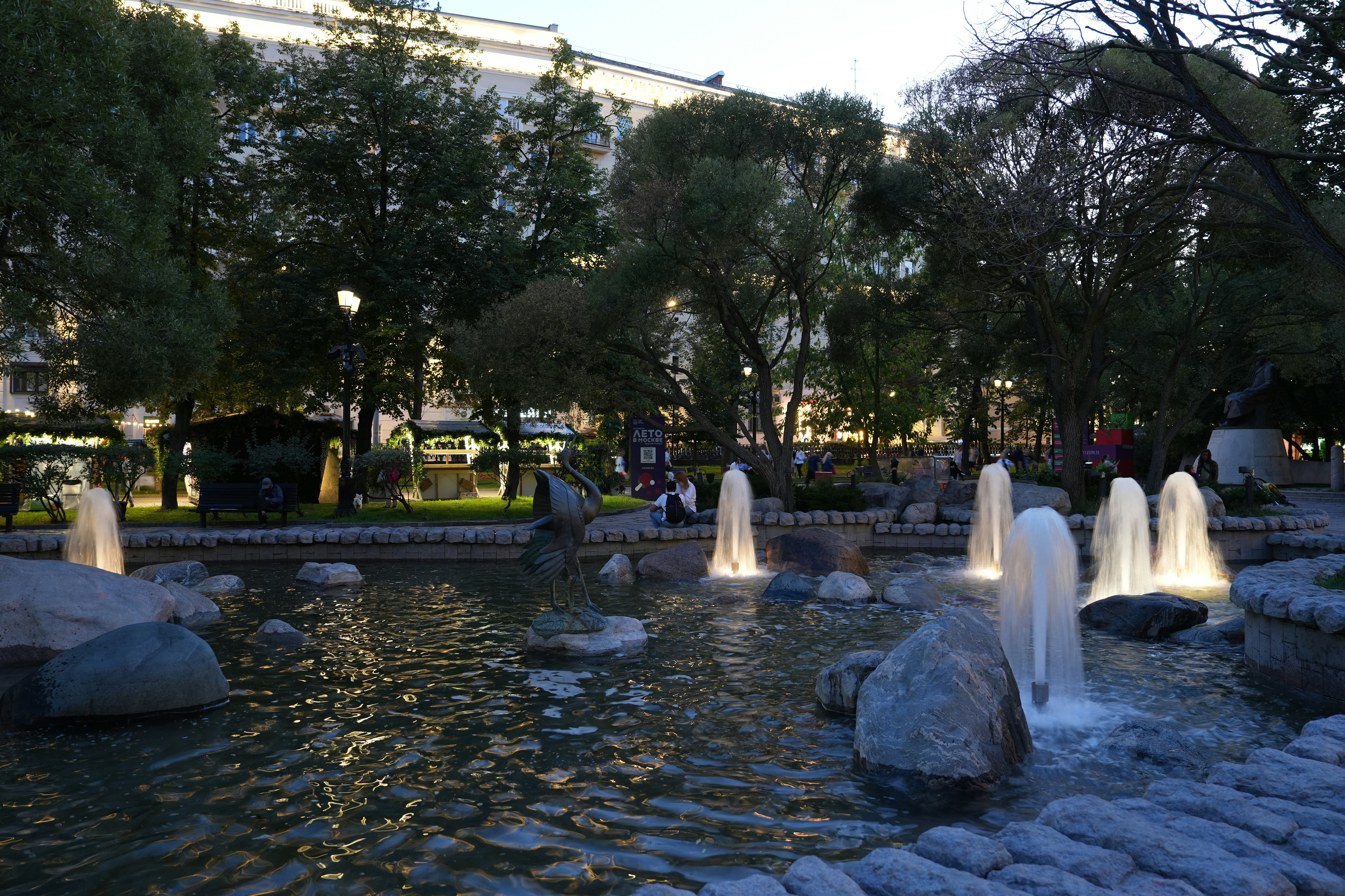 Fountains are illuminated in a tranquil park setting.