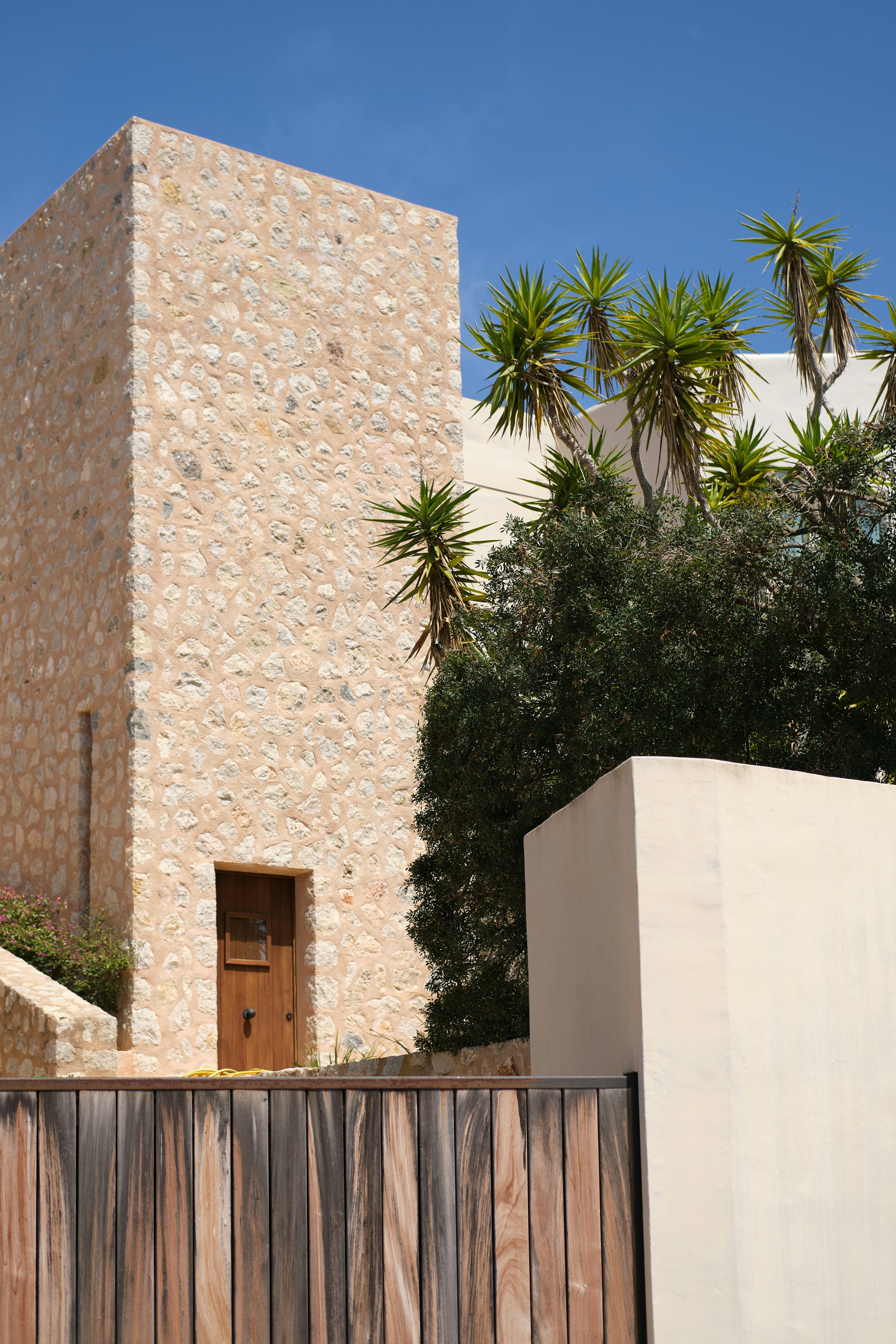 A stone building and plants under a blue sky.