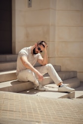 A man sits on stairs, looking thoughtful.