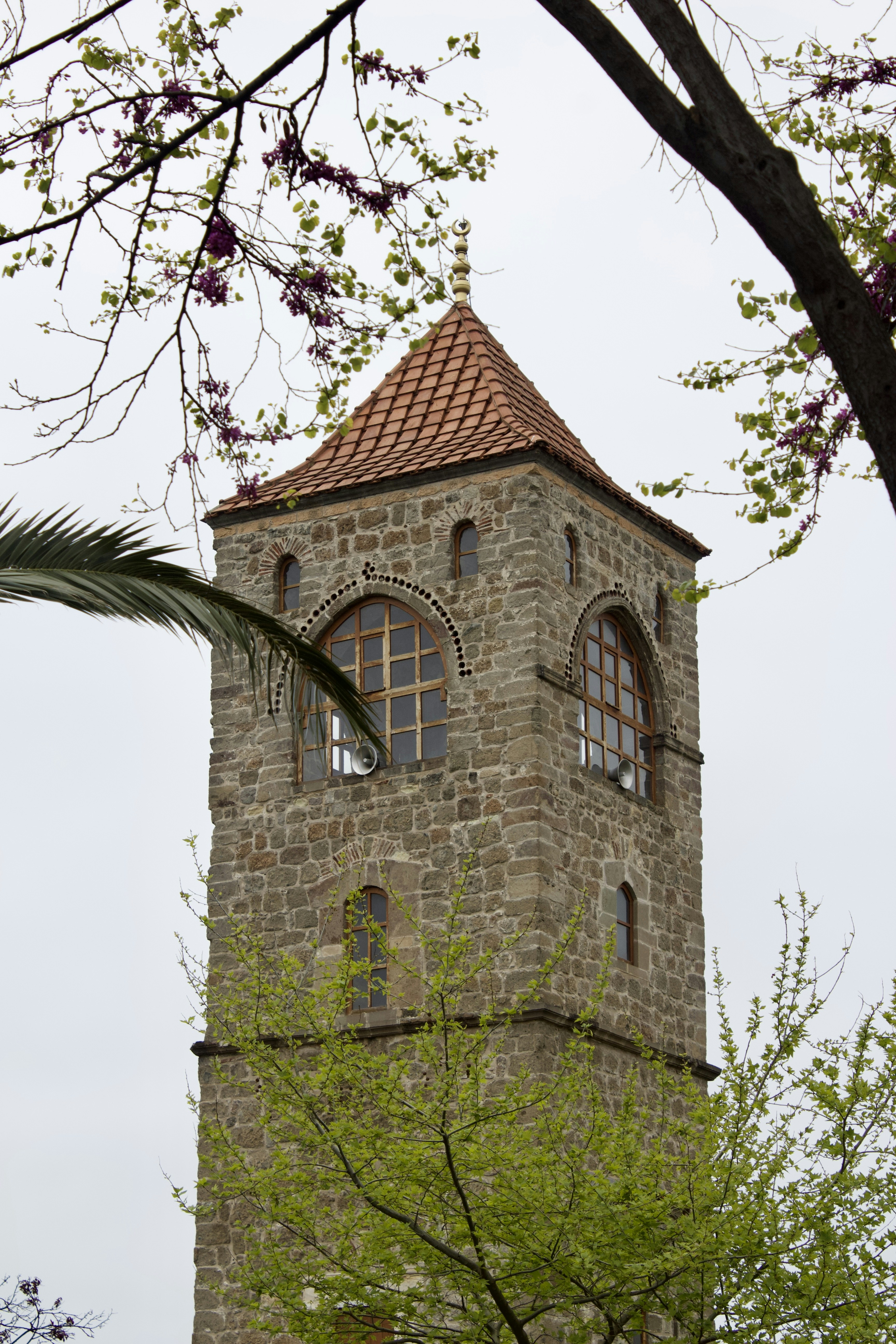 Stone tower rises towards the sky with trees.