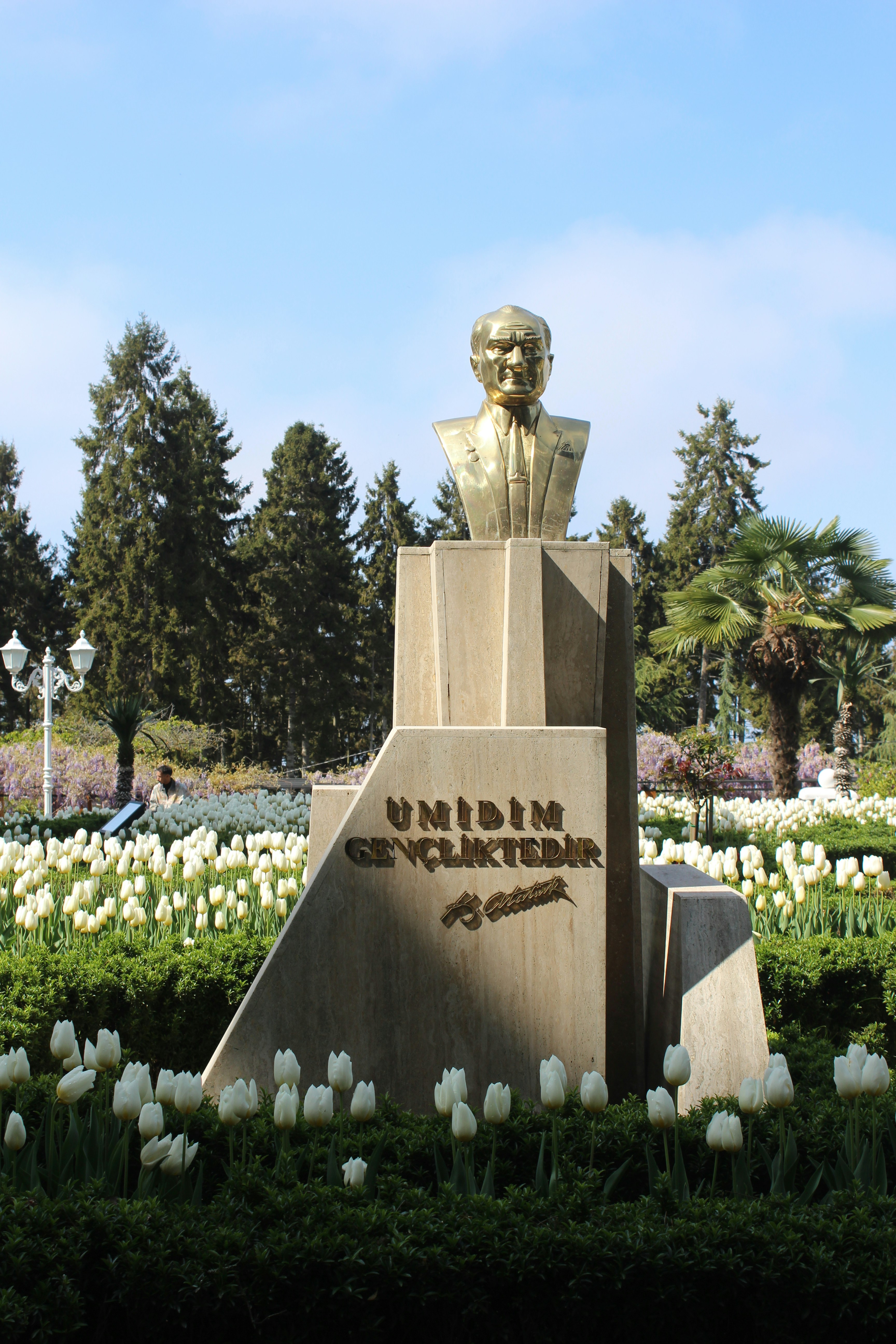 A statue of atatürk stands among tulips.