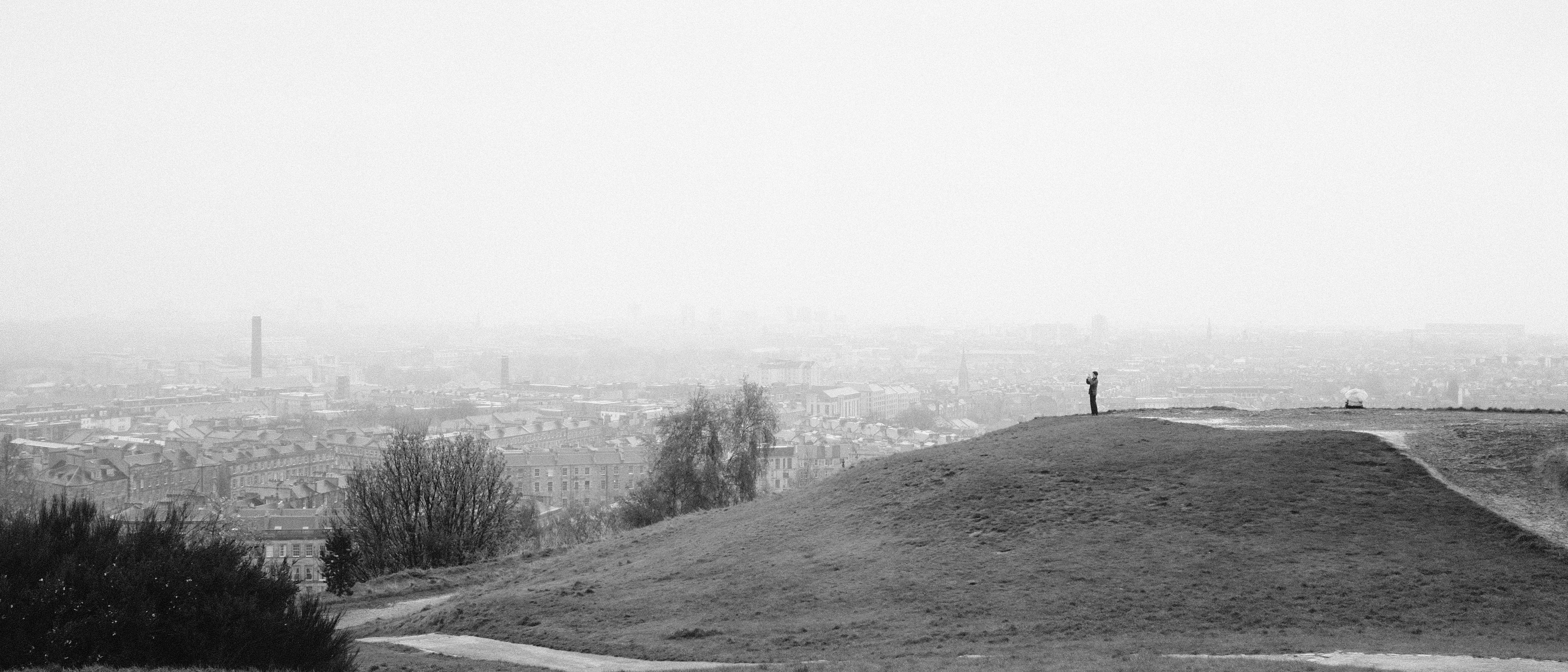A person stands on a grassy hill.