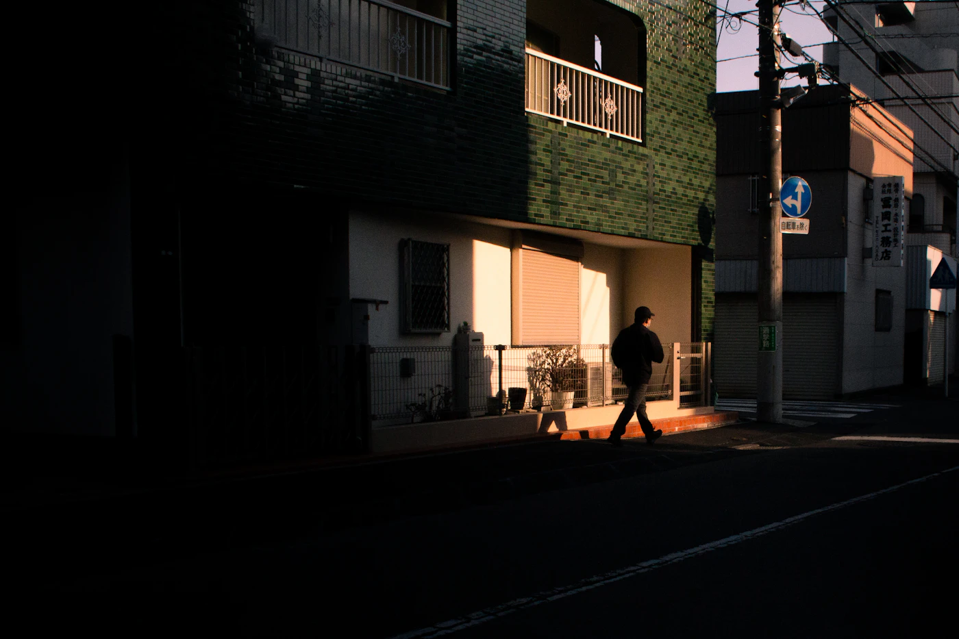 A person walking alone along a sunlit neighborhood street
