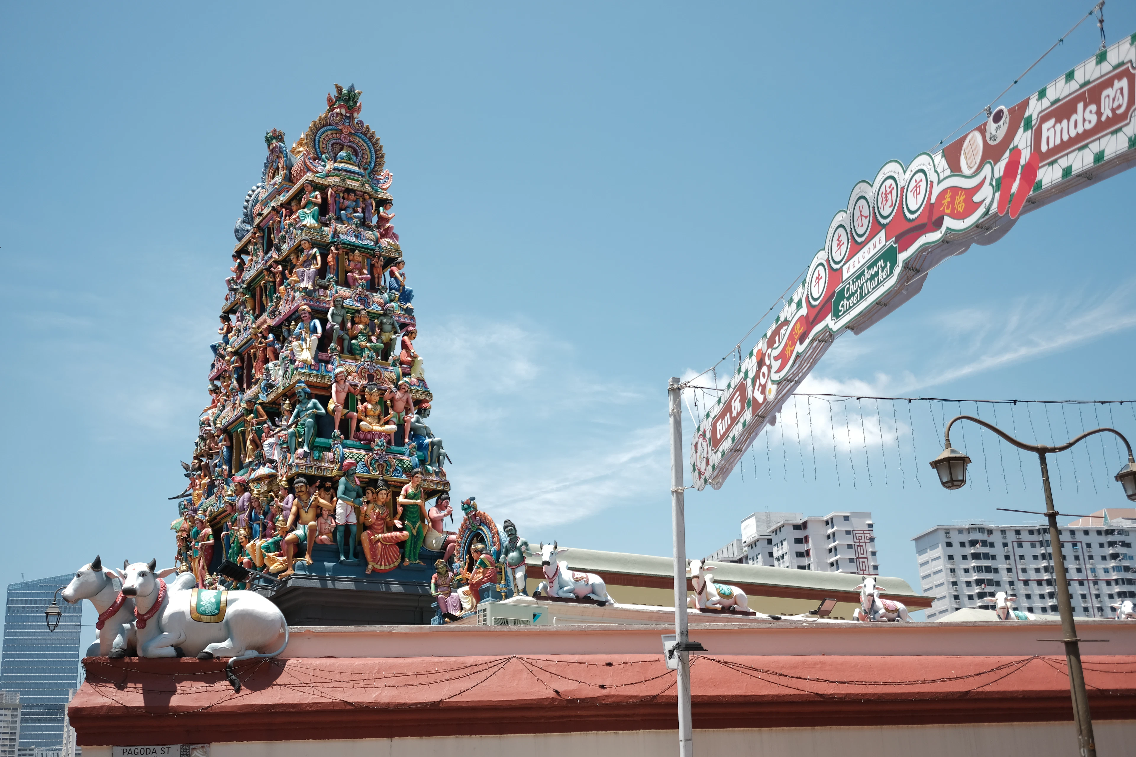 The figure-covered gopuram tower of Sri Mariamman Temple rising beside the Chinatown street arch in Singapore