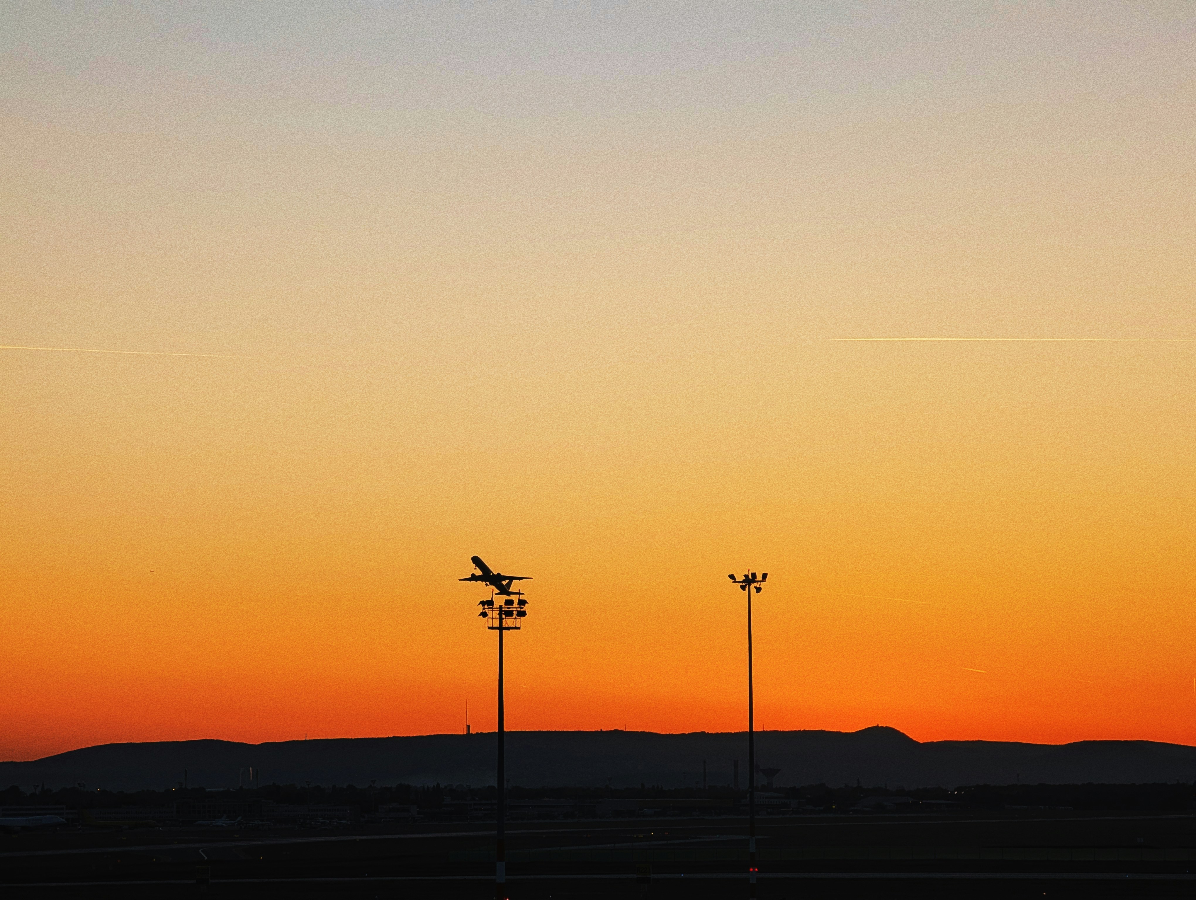 Um avião decola durante o pôr do sol.