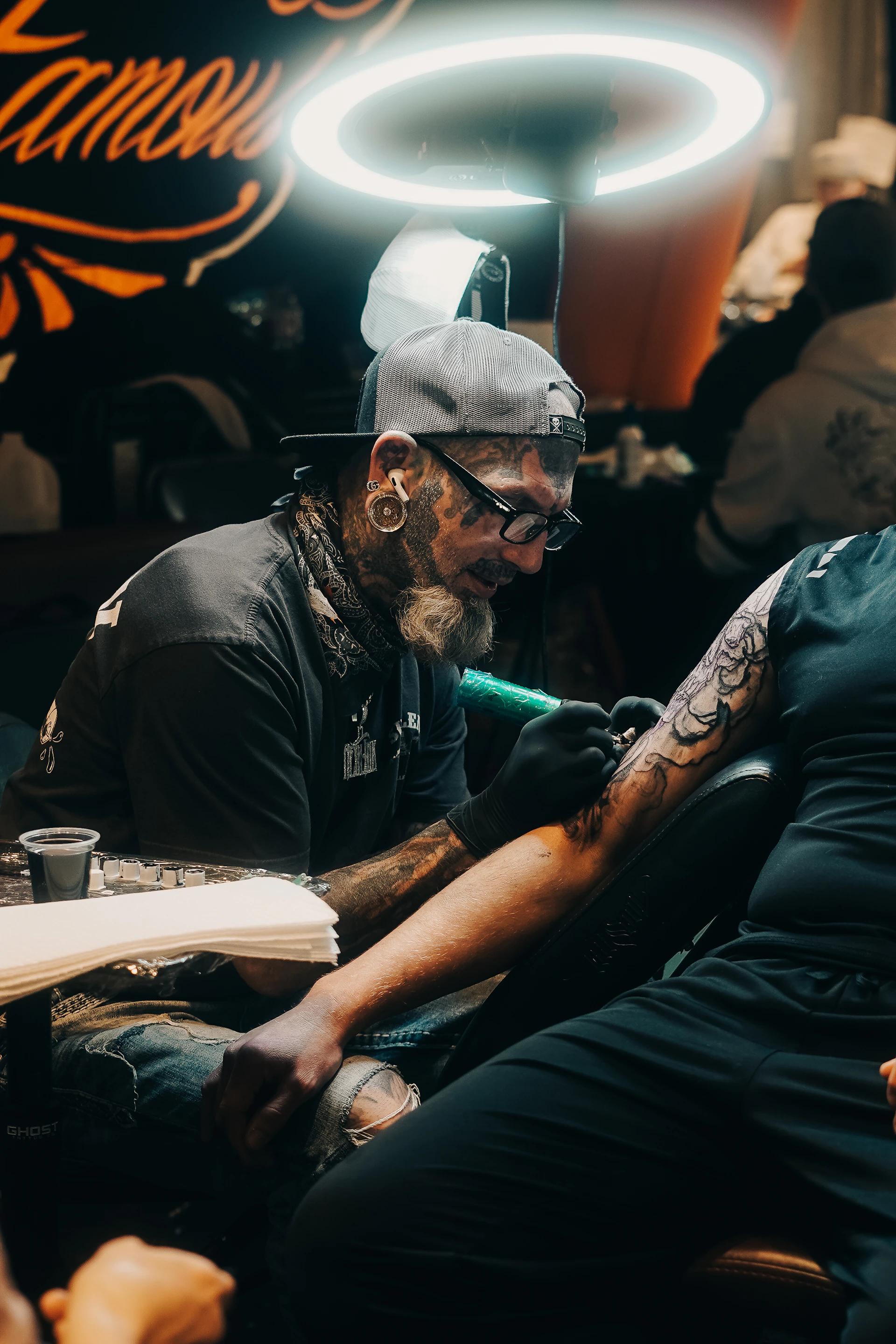A tattoo artist is working on a client's arm.