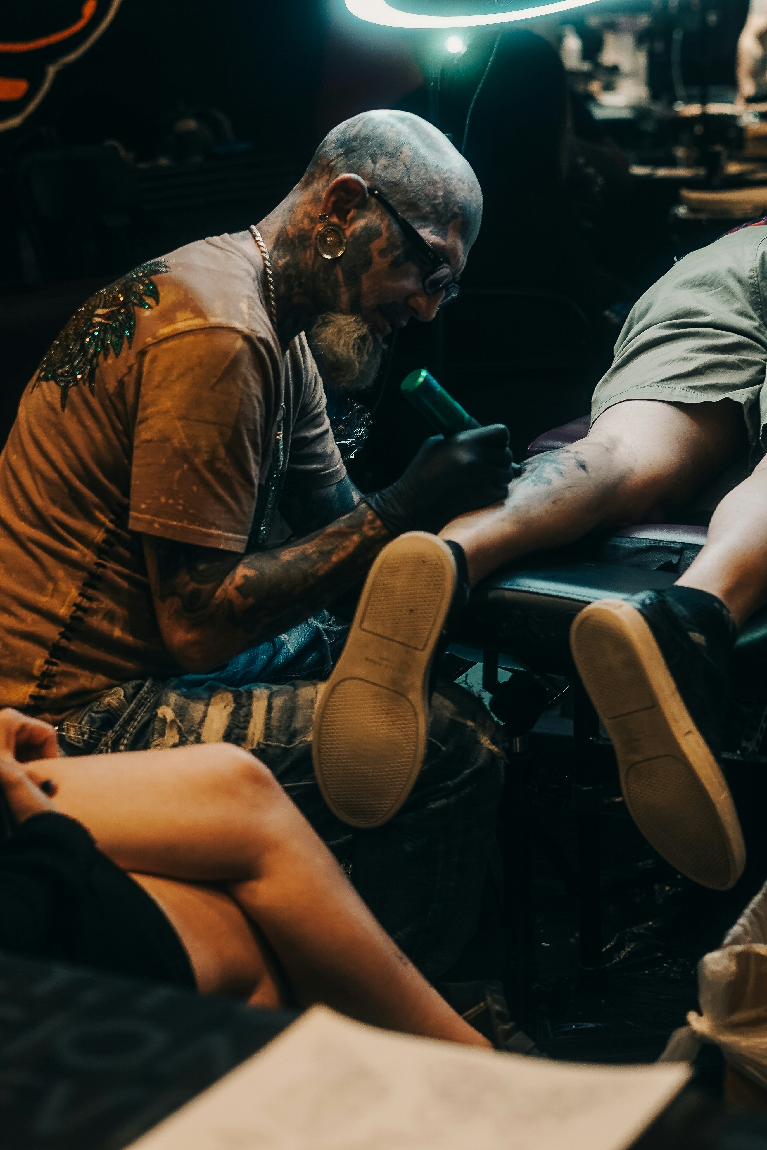 Un tatuador entinta un diseño en una pierna.