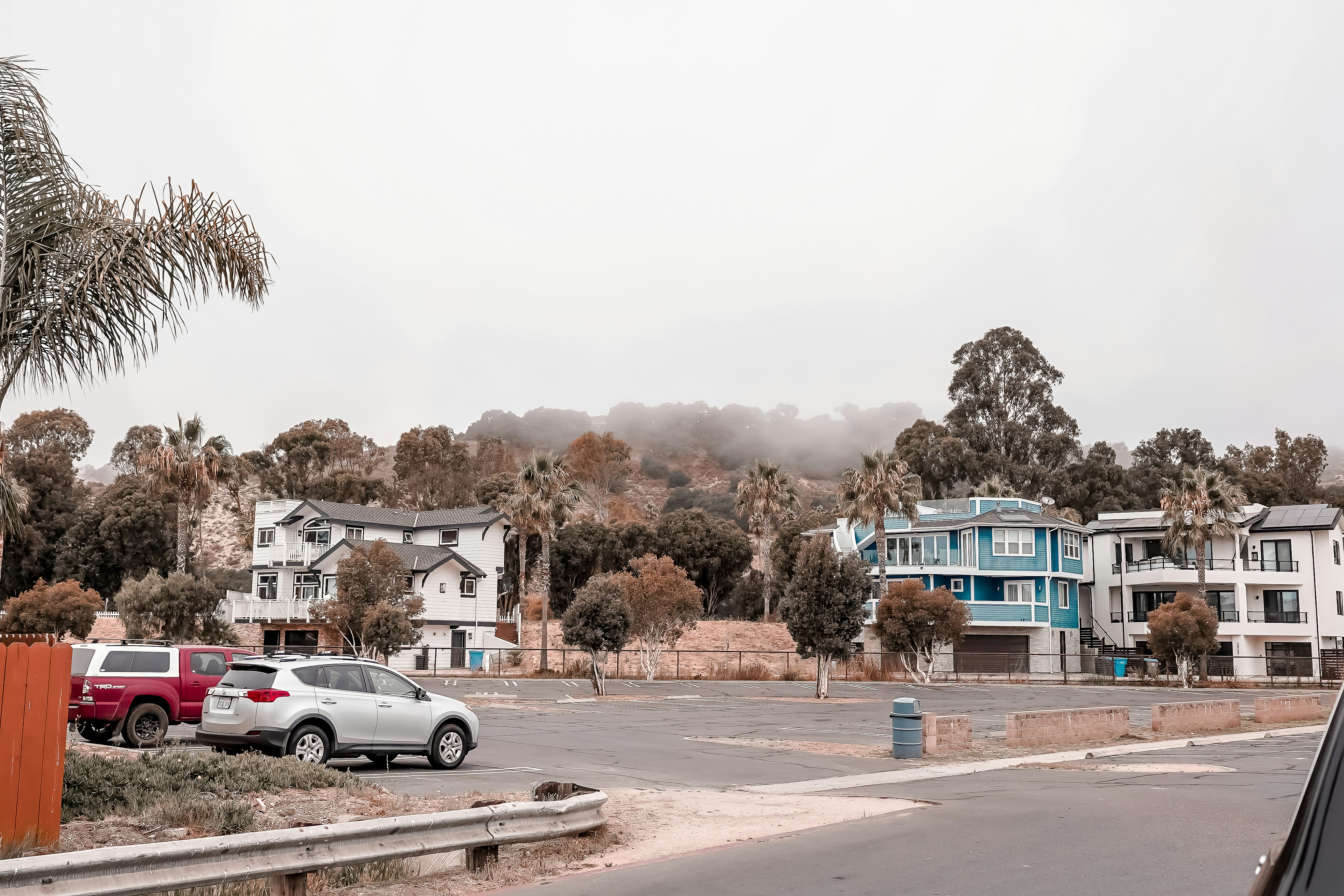 Las casas y los coches se encuentran cerca de una zona boscosa y brumosa.